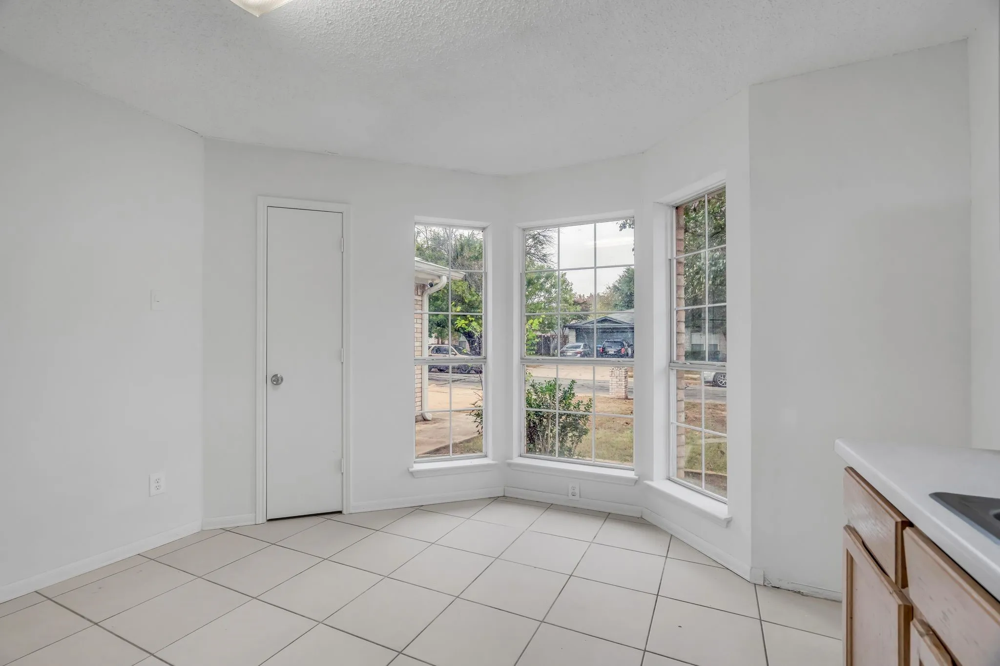 Unfurnished dining area featuring a textured ceiling, plenty of natural light, and light tile patterned floors