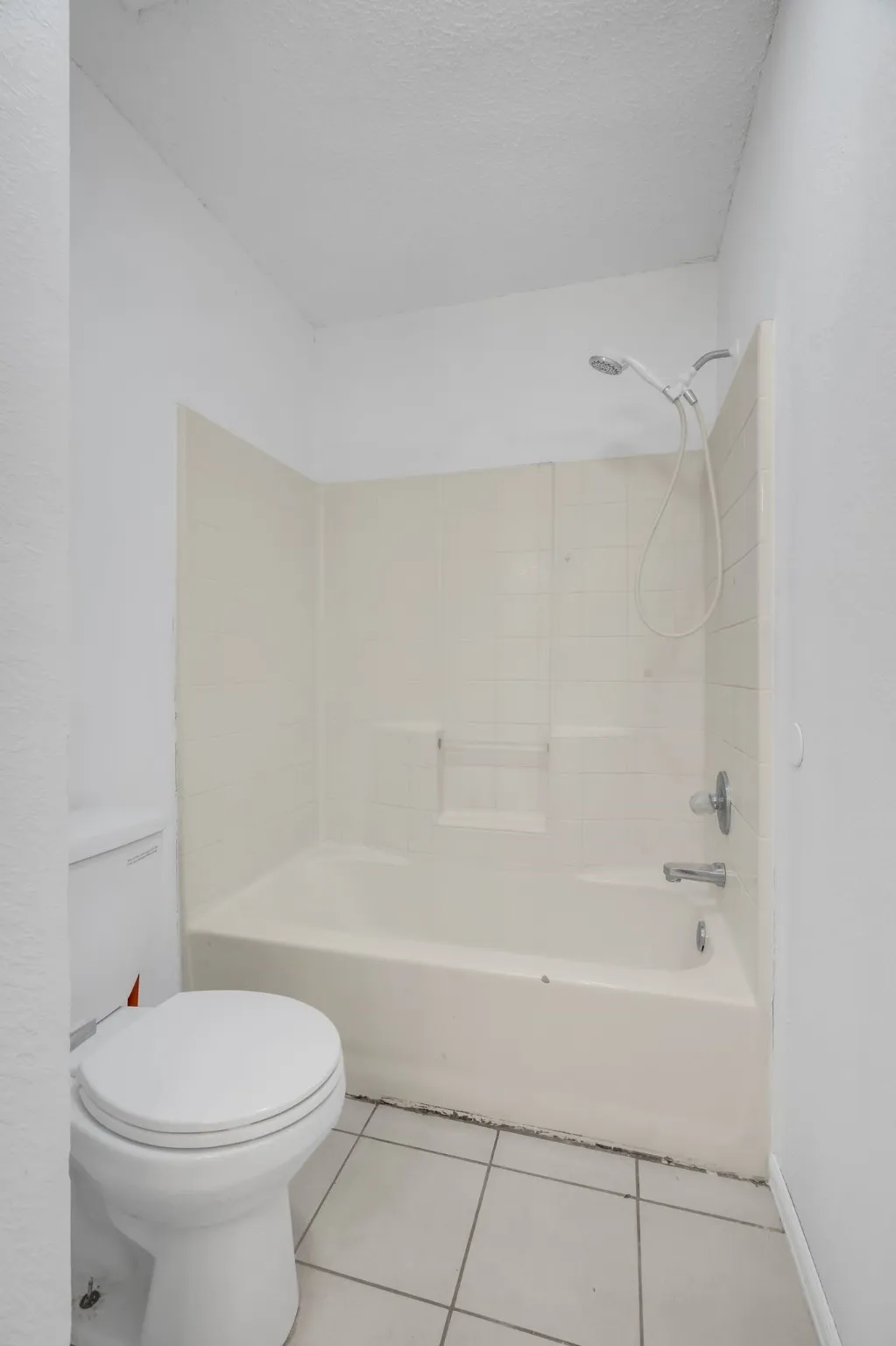 Full bath with tile patterned flooring, a textured ceiling, and shower / bathtub combination
