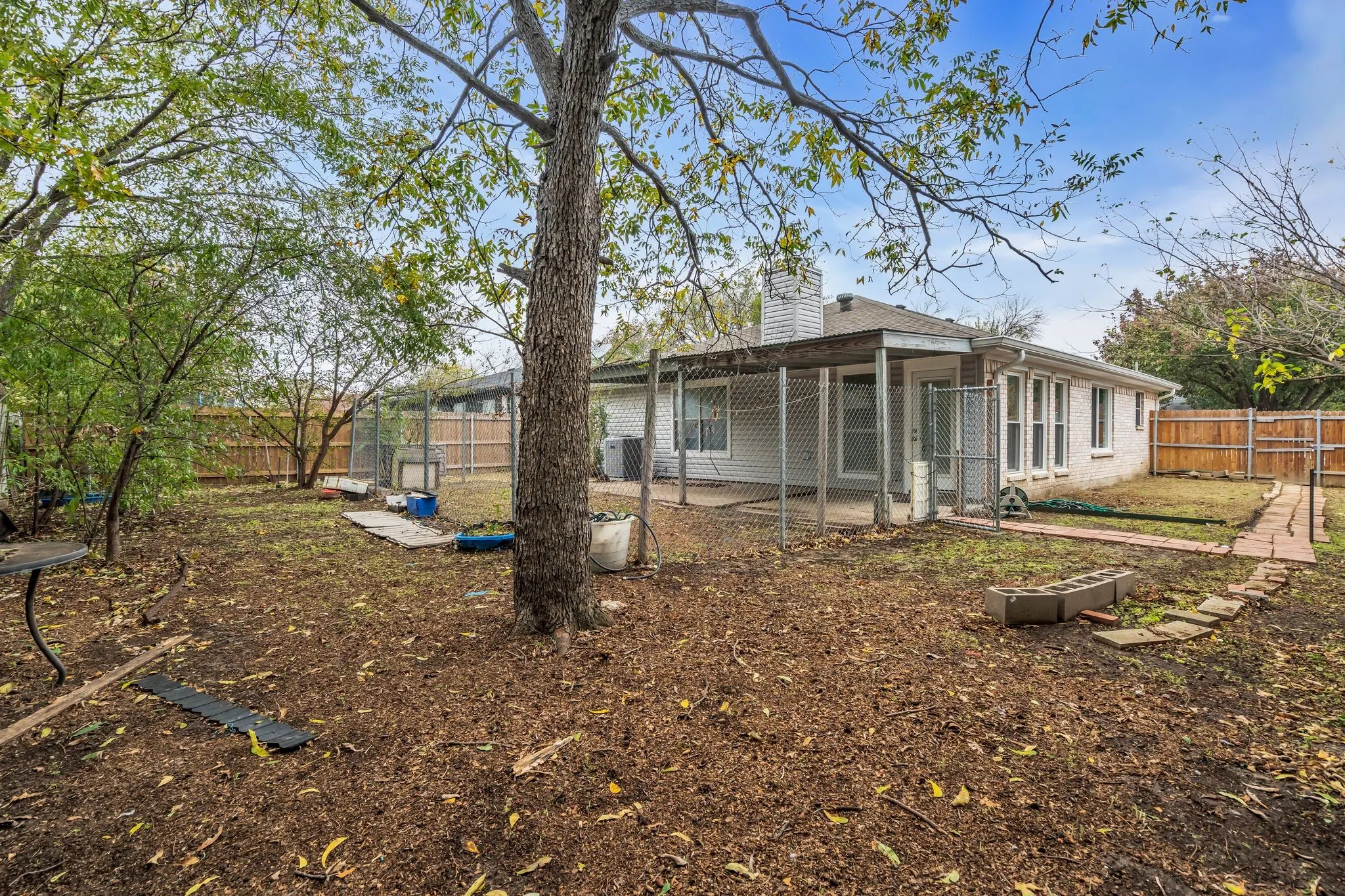 Back of house featuring a patio area, a fenced backyard, a chimney, and brick siding