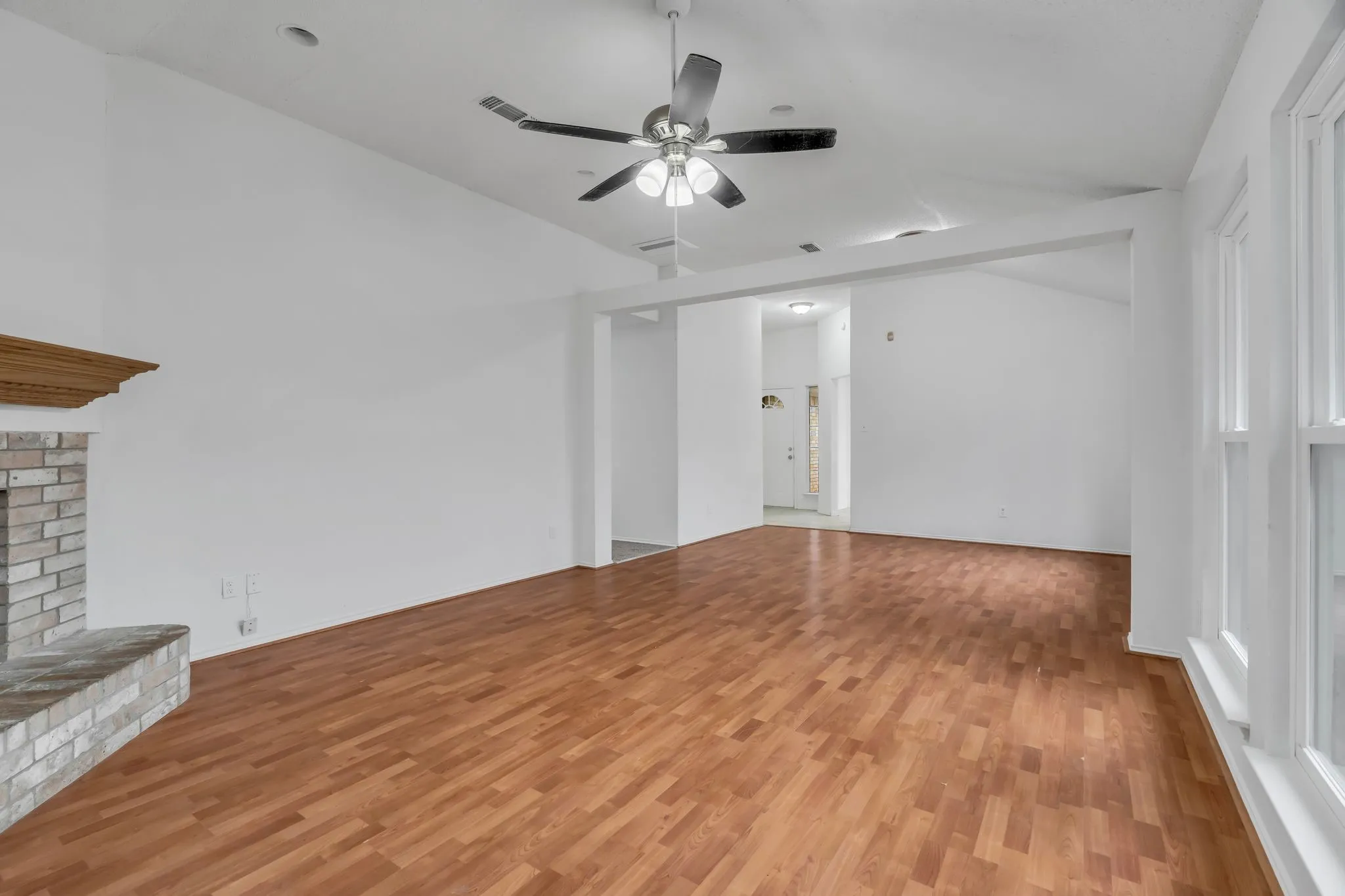 Unfurnished living room with vaulted ceiling, light wood-style floors, ceiling fan, and a fireplace