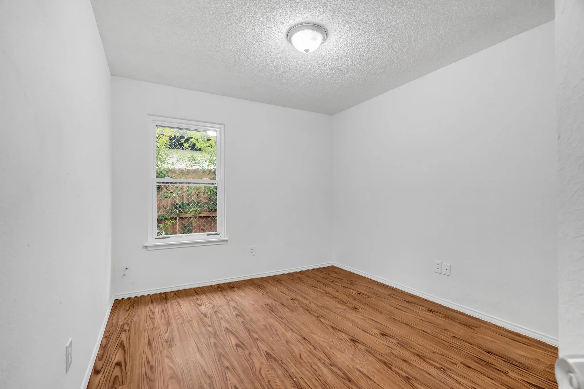 Unfurnished room featuring wood finished floors and a textured ceiling