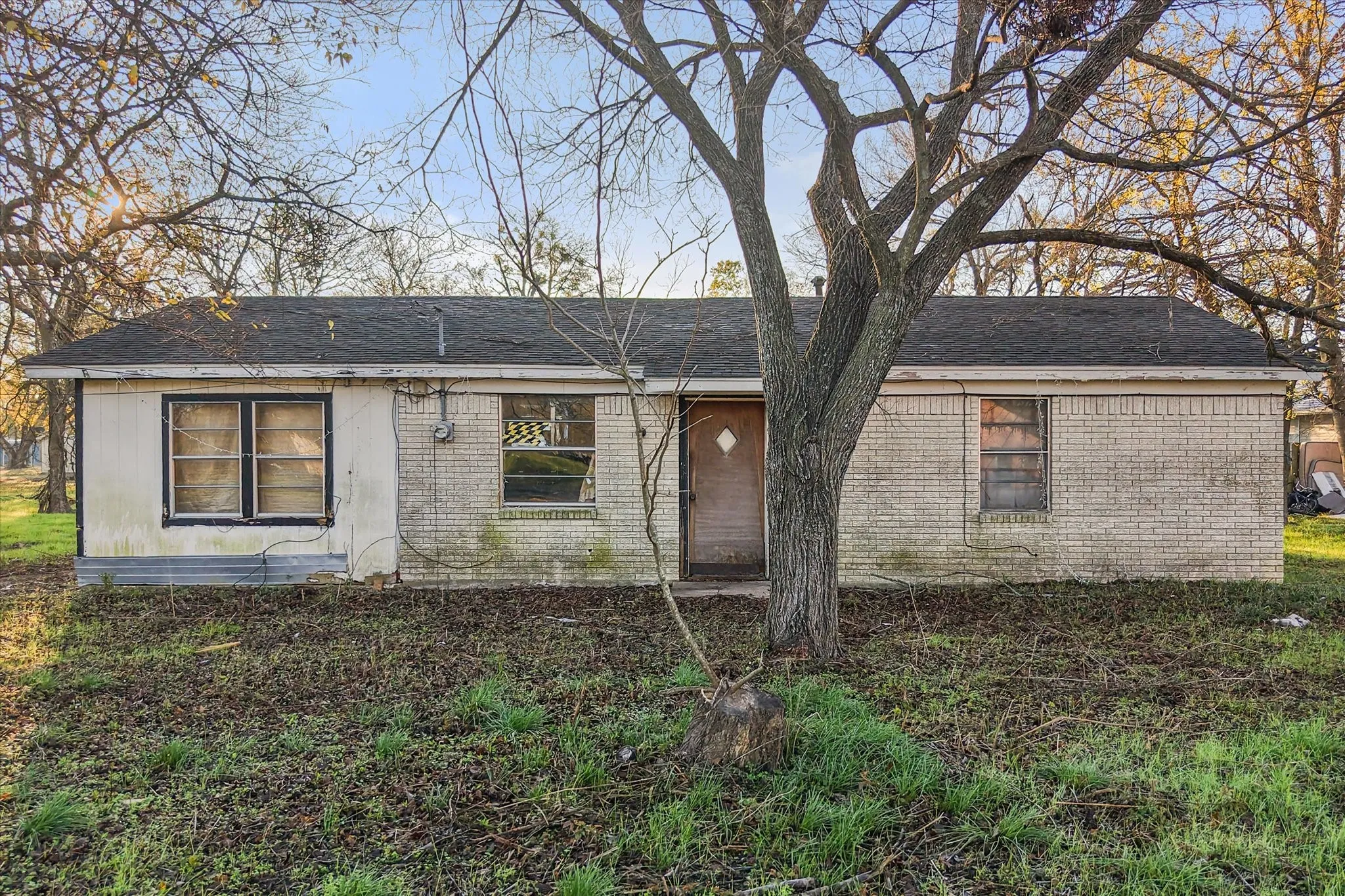 View of front of house featuring brick siding and roof with shingles