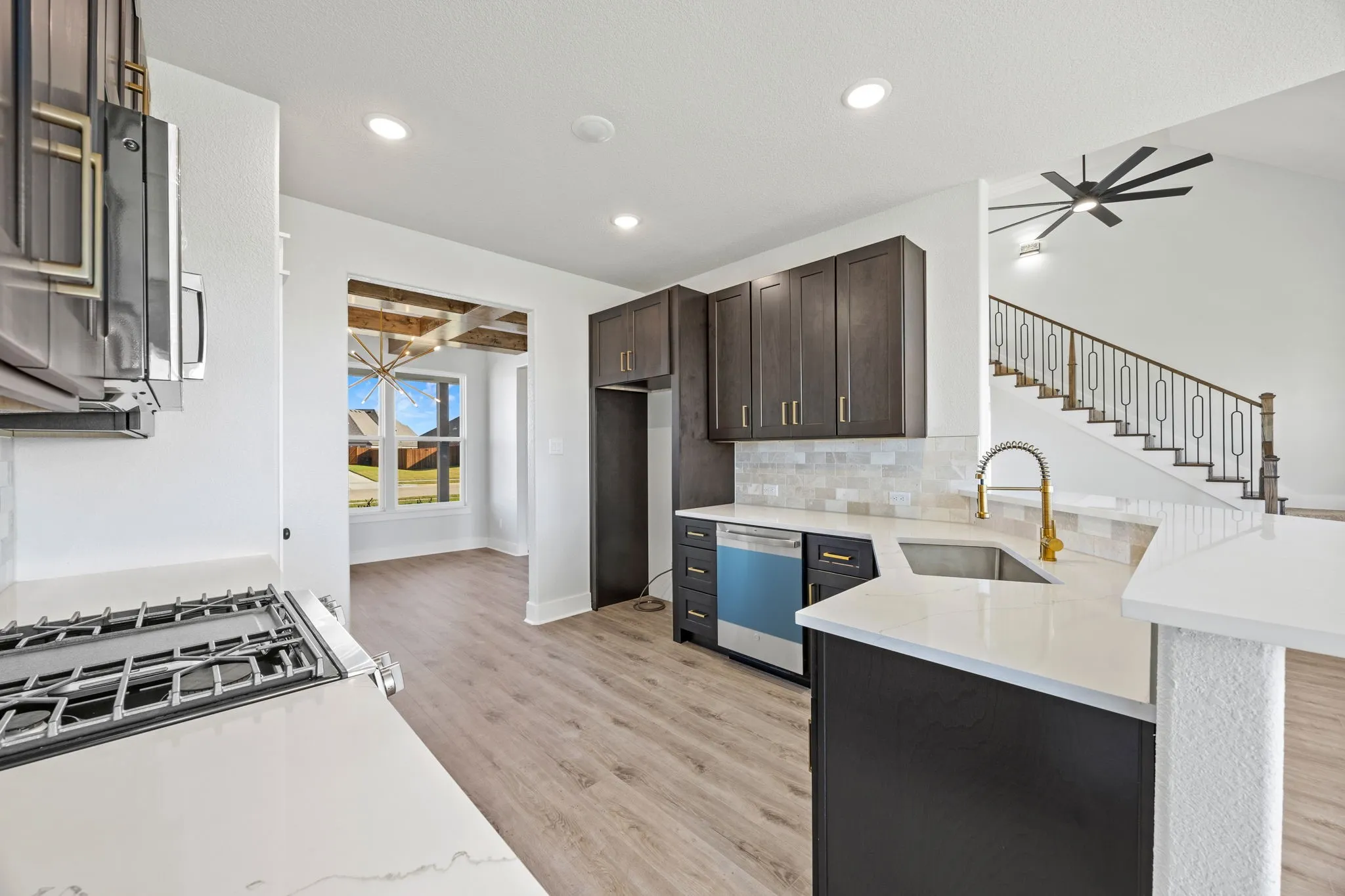 Kitchen featuring light stone countertops, light wood-style flooring, decorative backsplash, appliances with stainless steel finishes, and a peninsula