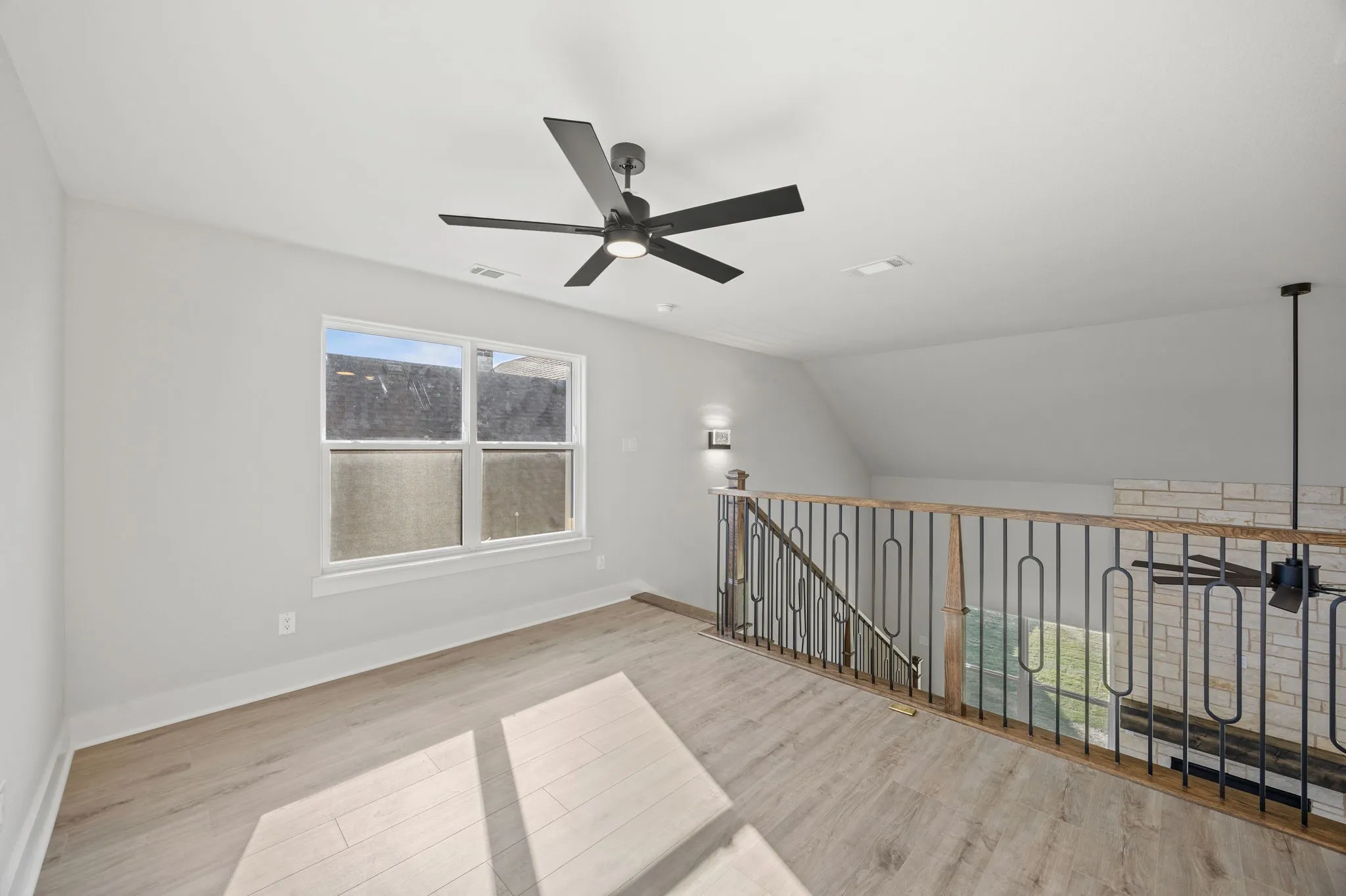 Empty room with light wood-type flooring, vaulted ceiling, and ceiling fan