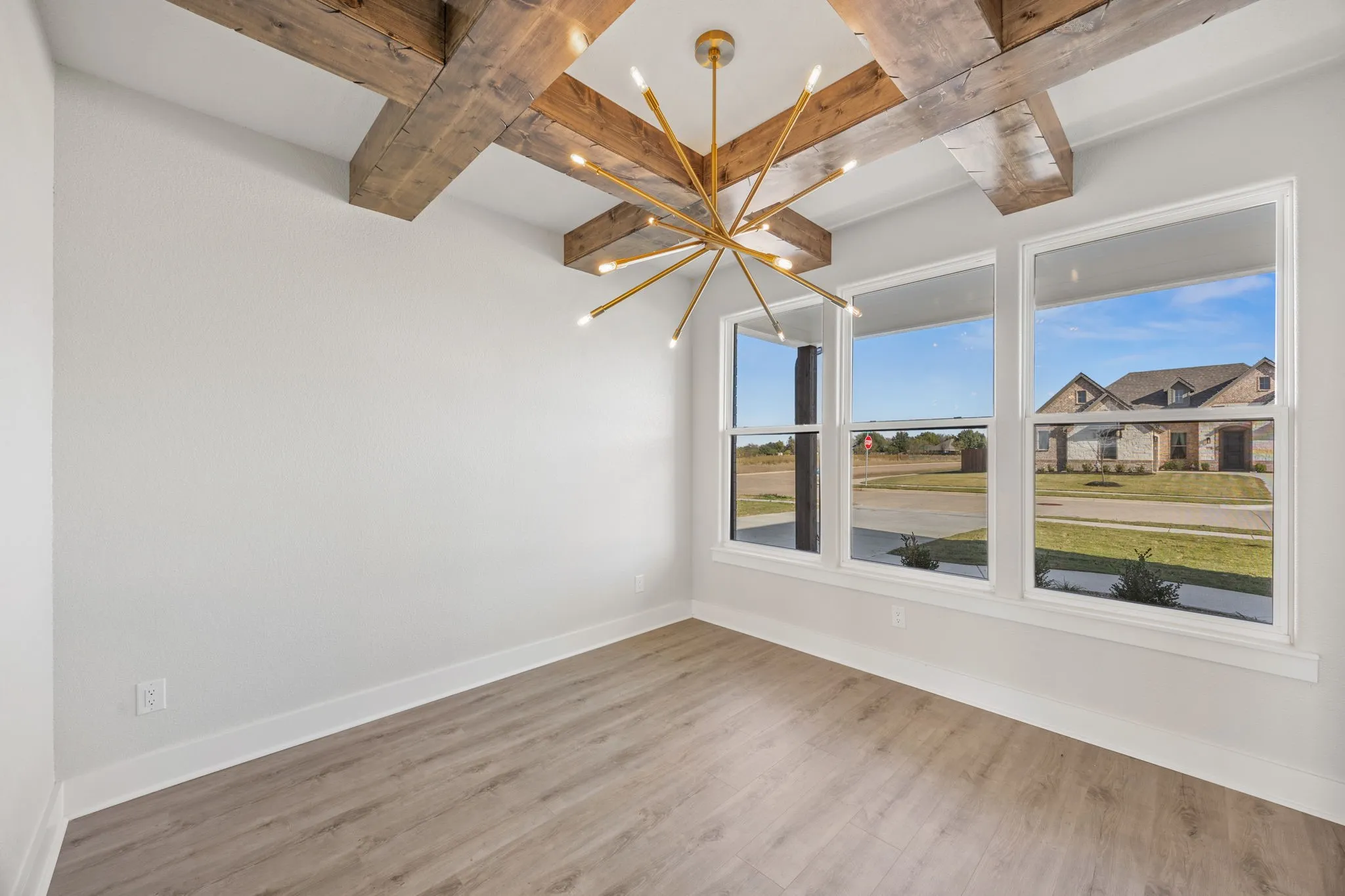 Spare room featuring wood finished floors, beam ceiling, a chandelier, and coffered ceiling