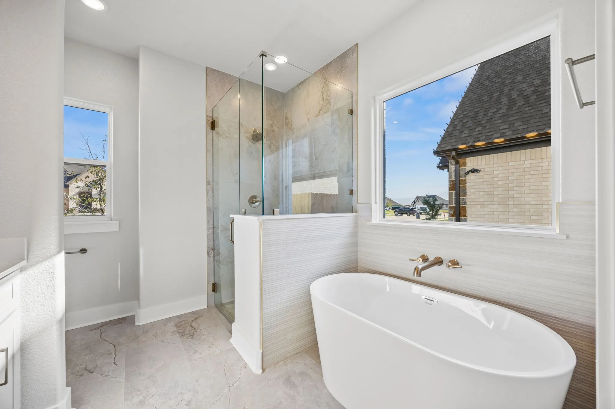 Full bathroom featuring a freestanding bath, light marble finish flooring, a marble finish shower, vanity, and recessed lighting
