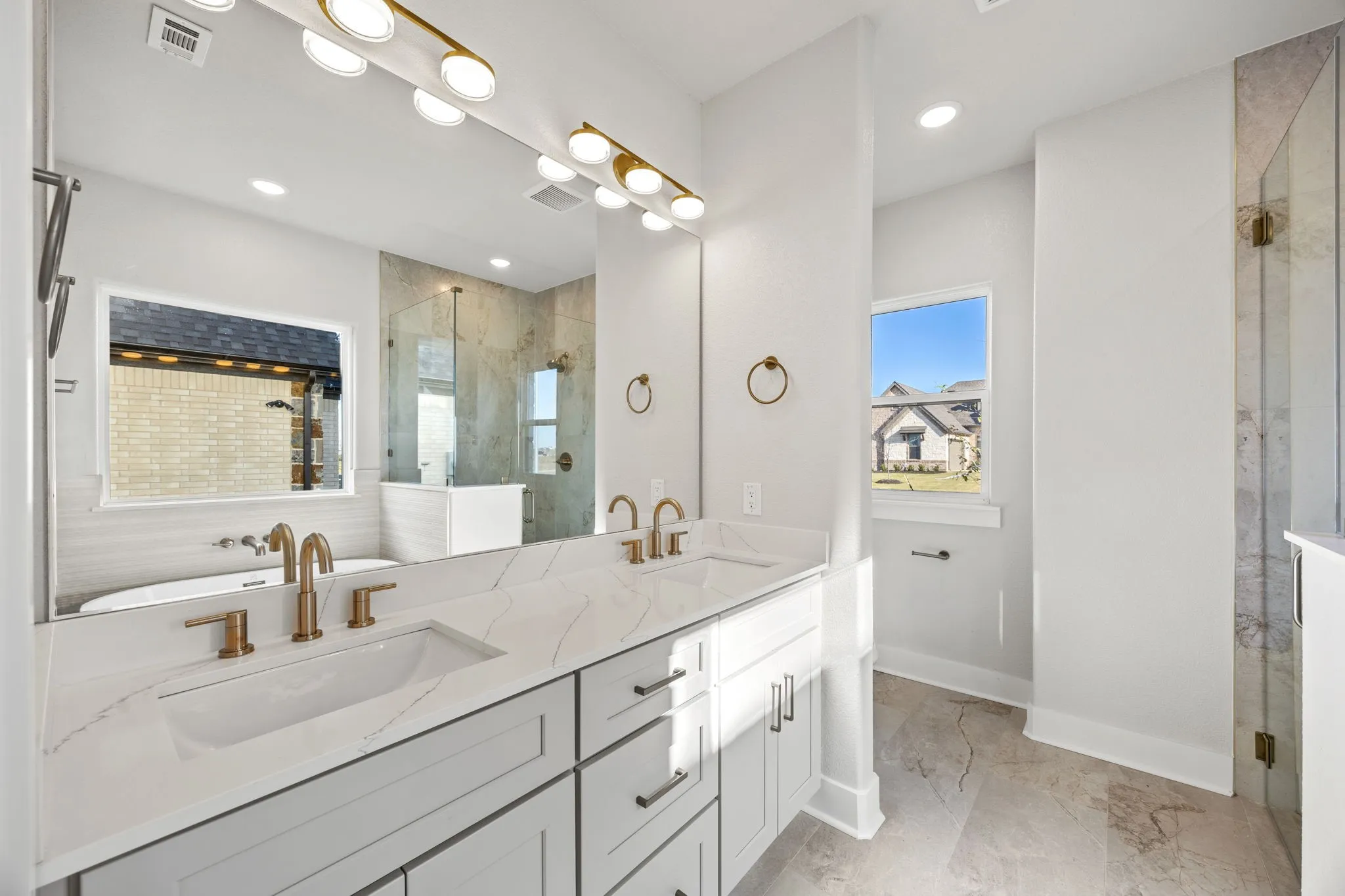 Bathroom with a stall shower, double vanity, and light marble finish flooring