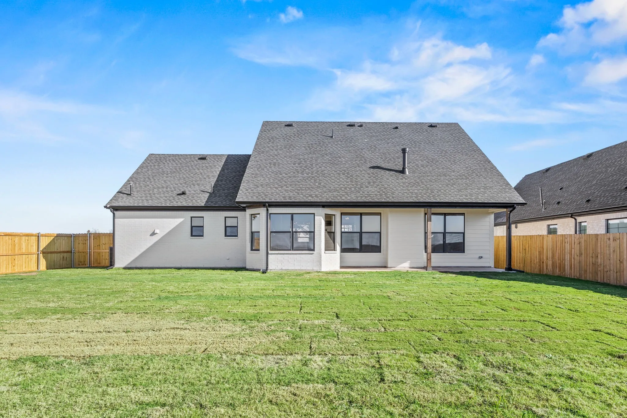 Back of property featuring a fenced backyard, roof with shingles, and a patio area