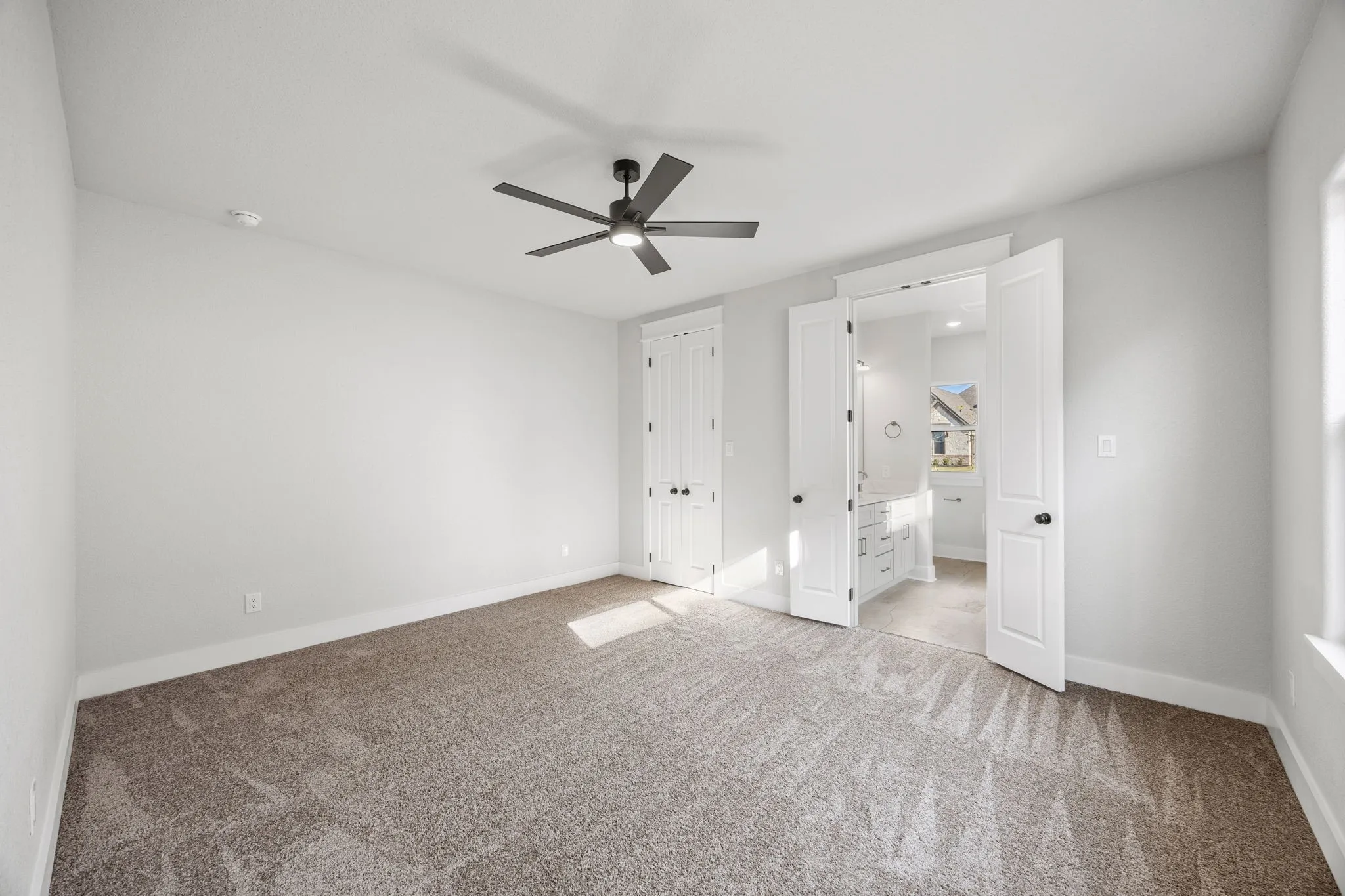 Unfurnished bedroom featuring ensuite bath, carpet flooring, a ceiling fan, and a closet