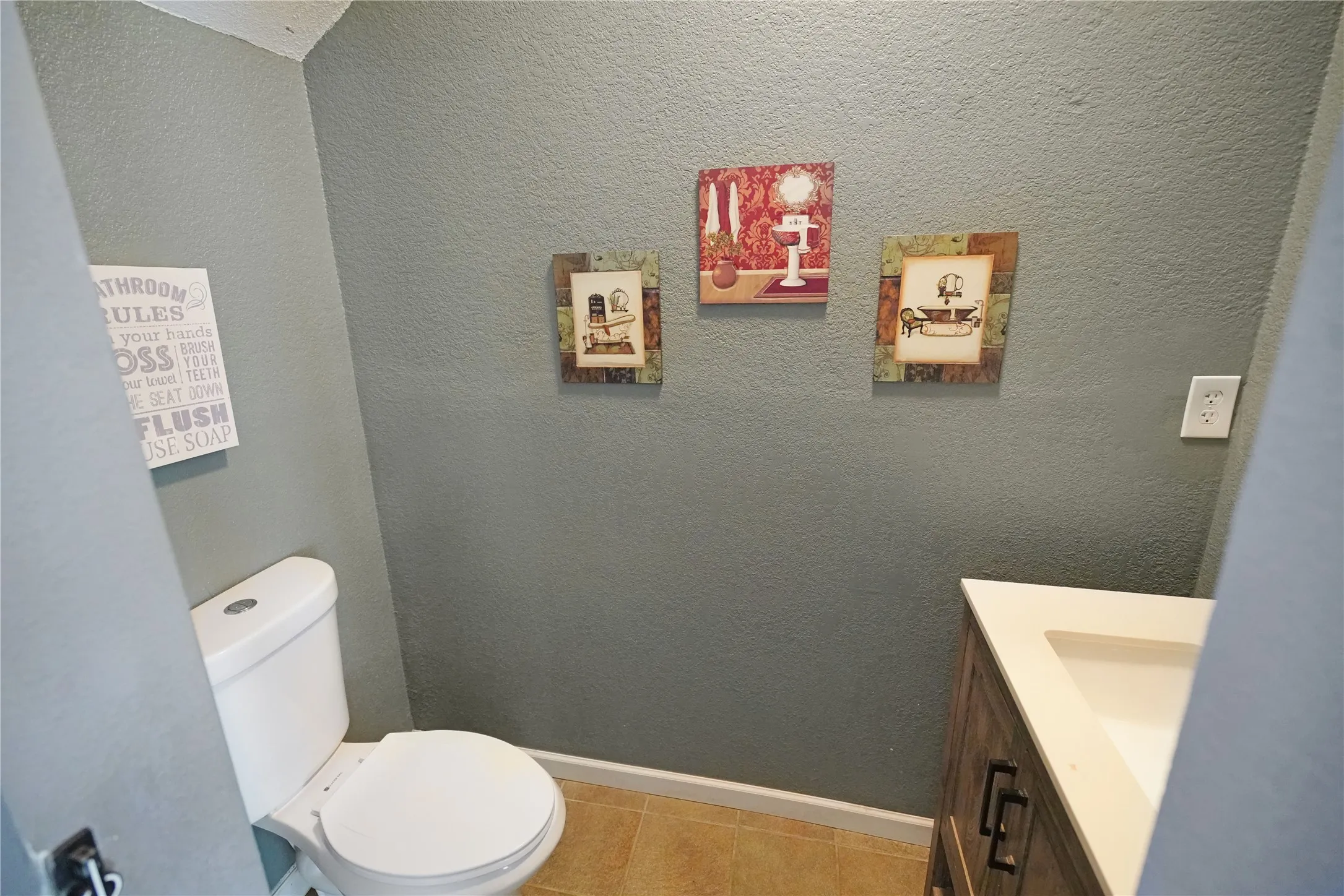 Half bathroom with vanity, a textured wall, and light tile patterned flooring