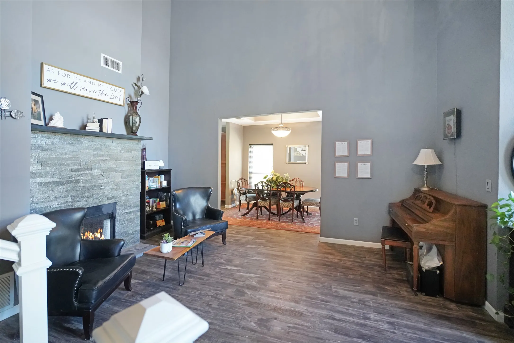 Sitting room with a towering ceiling, a fireplace, and dark wood-style floors