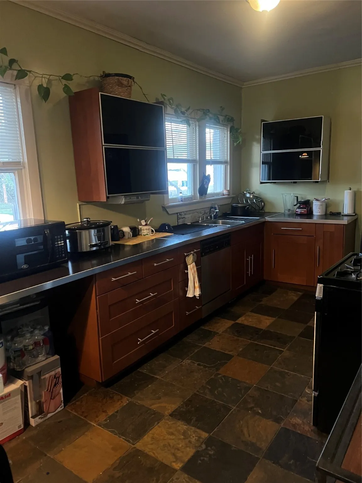Kitchen with range, crown molding, dishwashing machine, open shelves, and stone tile flooring