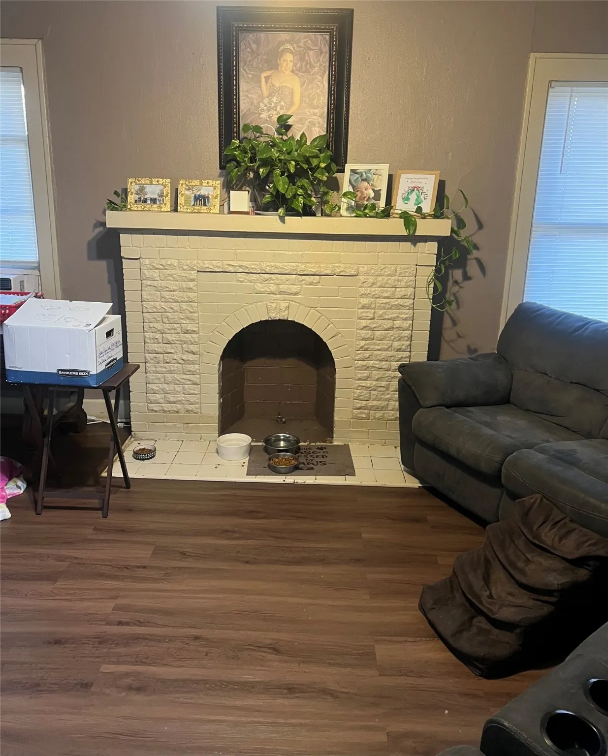 Living area with wood finished floors, a brick fireplace, and a textured wall