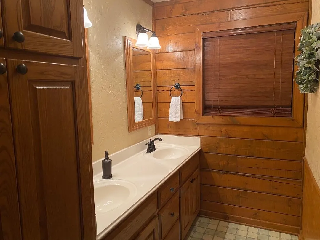 Bathroom with a textured wall, double vanity, and wood walls
