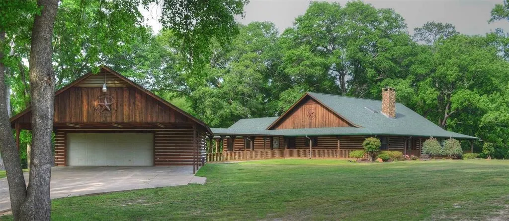 View of front of house featuring a front yard, a chimney, an outdoor structure, a detached garage, and driveway