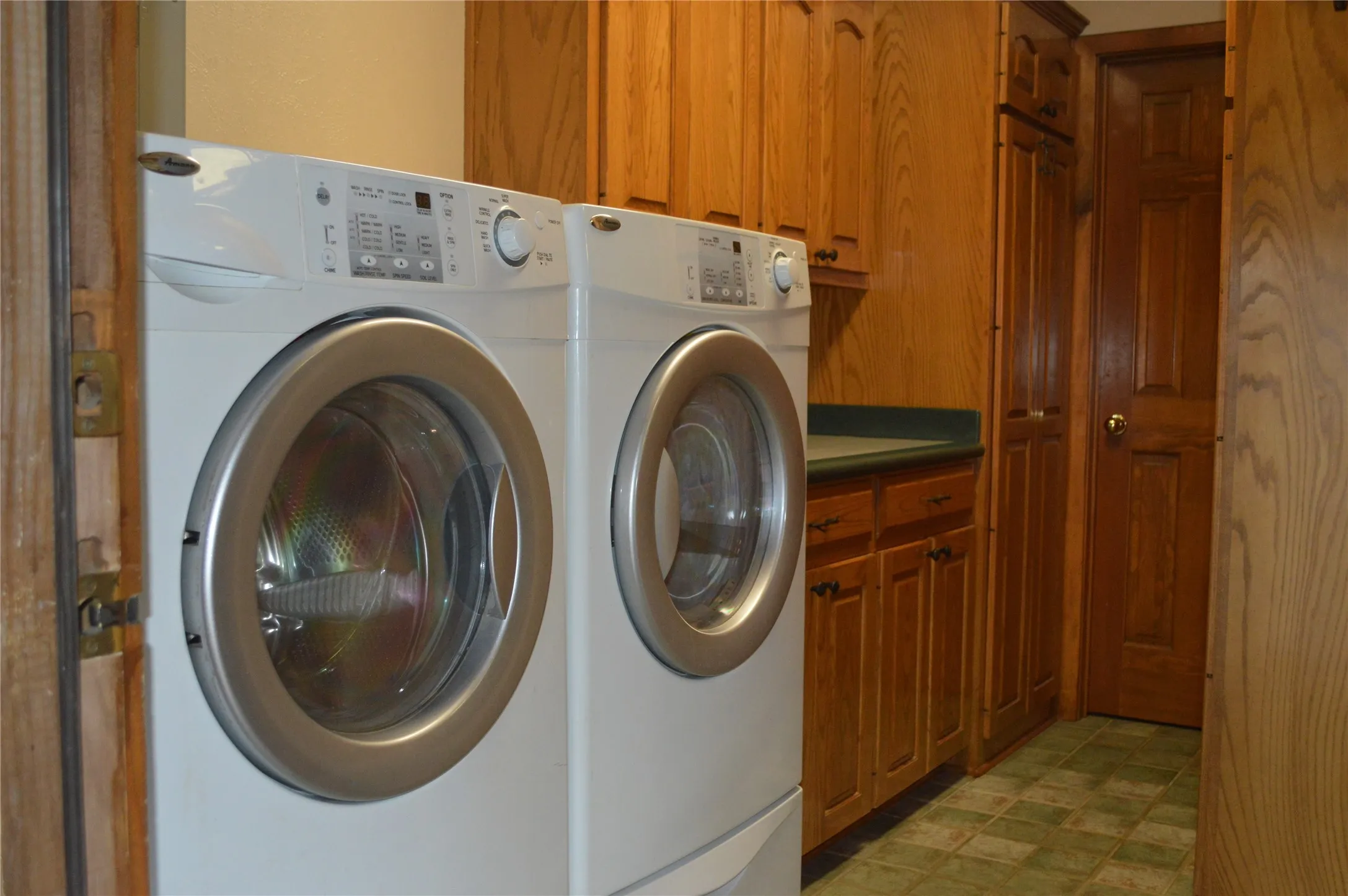 Laundry room featuring light floors, cabinet space, and washing machine and clothes dryer
