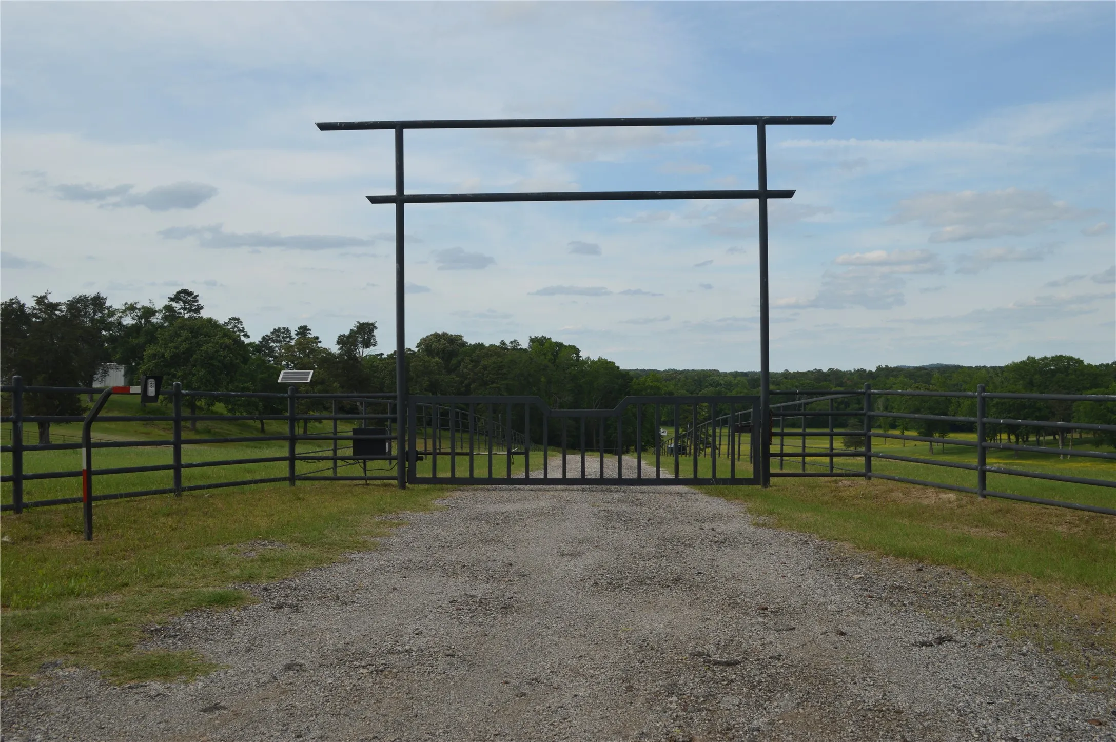 View of dirt / gravel road with a gate, a view of rural / pastoral area, and a gated entry
