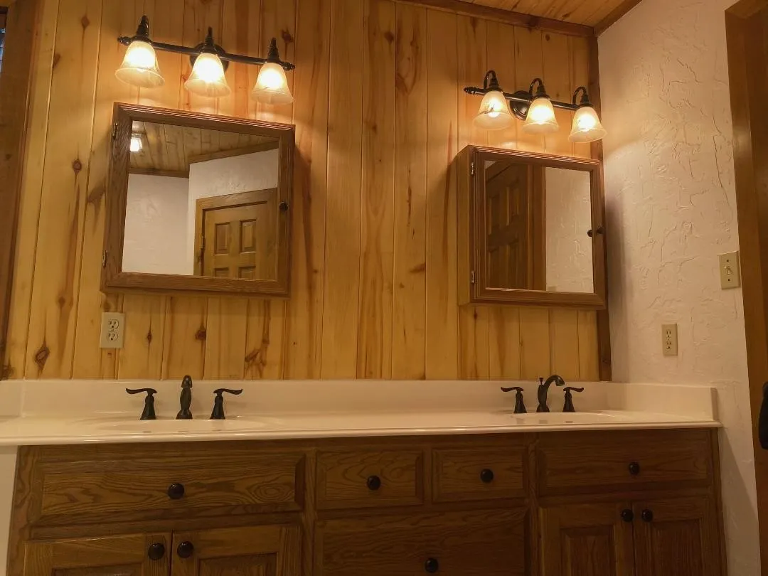 Full bathroom featuring a textured wall and double vanity