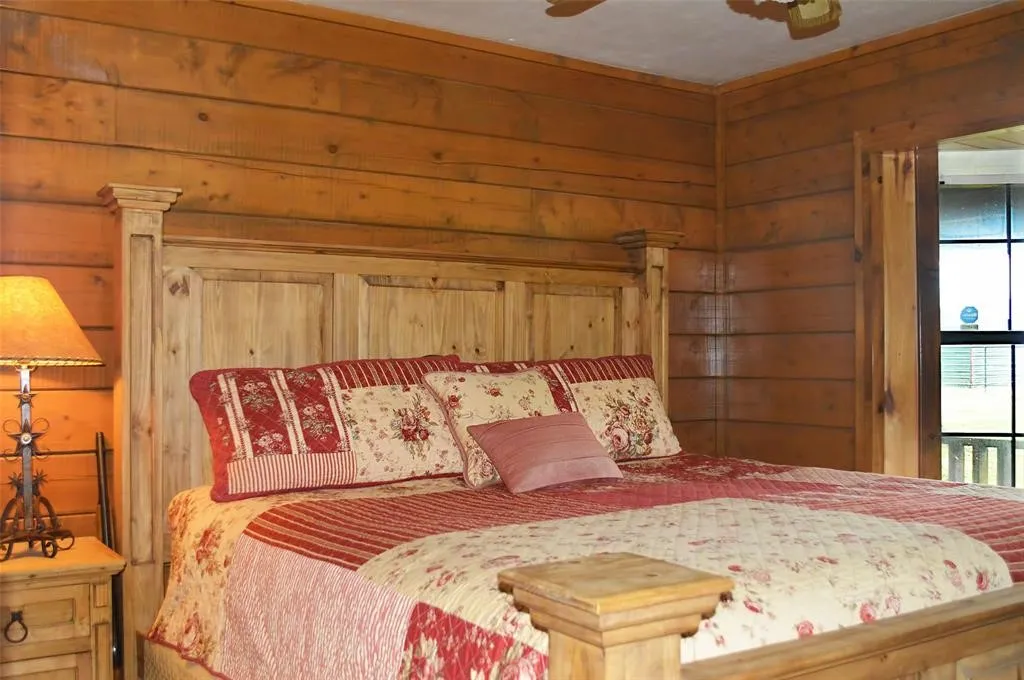 Bedroom with wood walls and ceiling fan