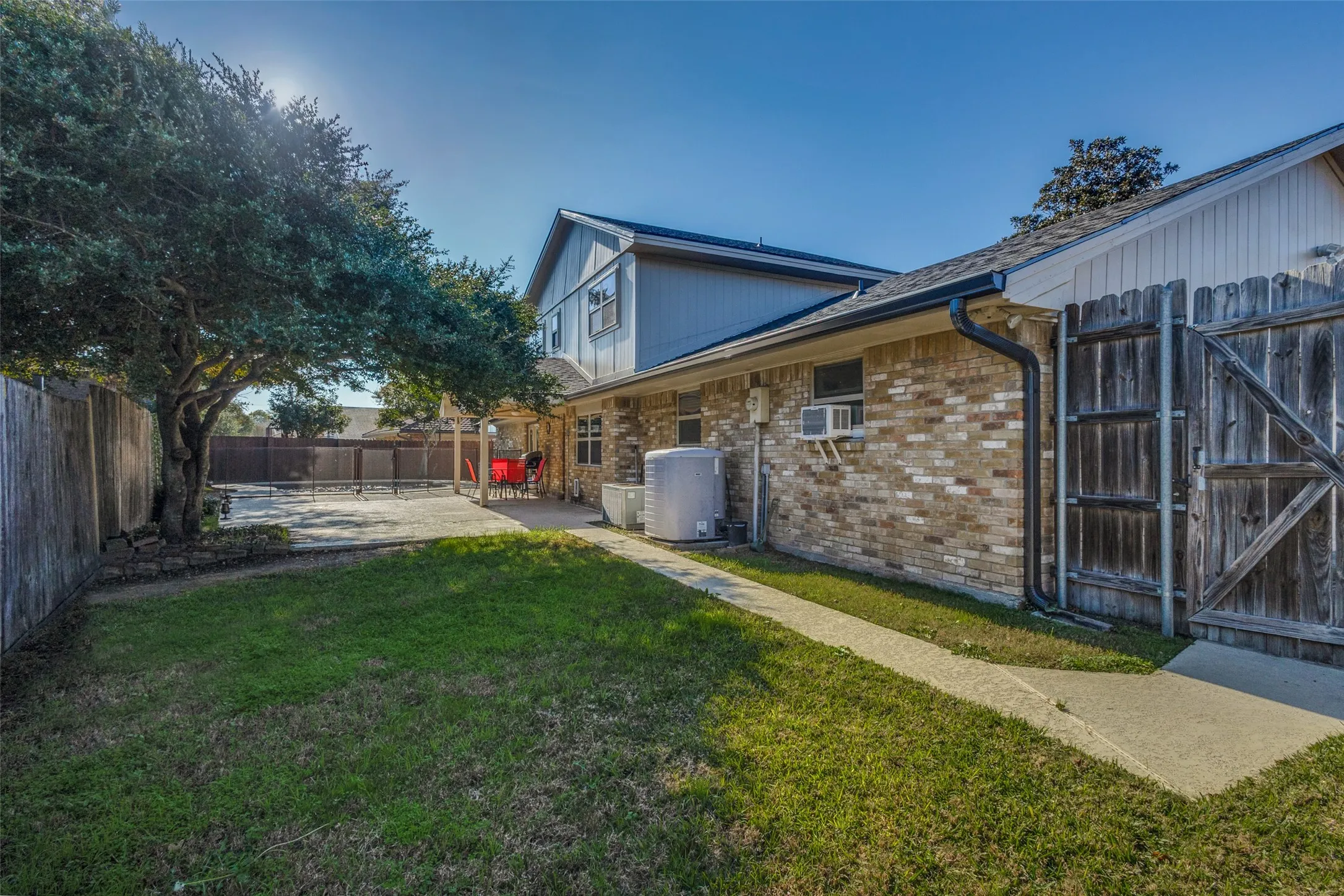 Fenced backyard with a patio, porch and Pool  and a gate to the parking area.