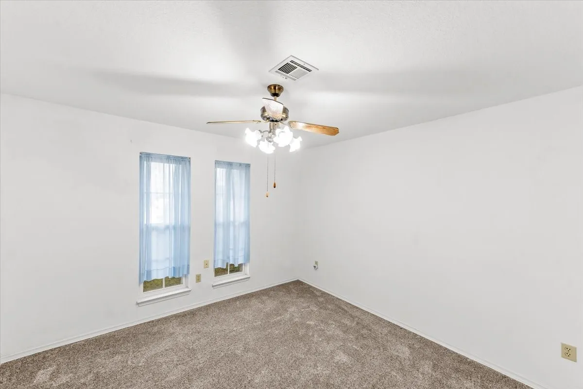 Carpeted empty room featuring ceiling fan and baseboards
