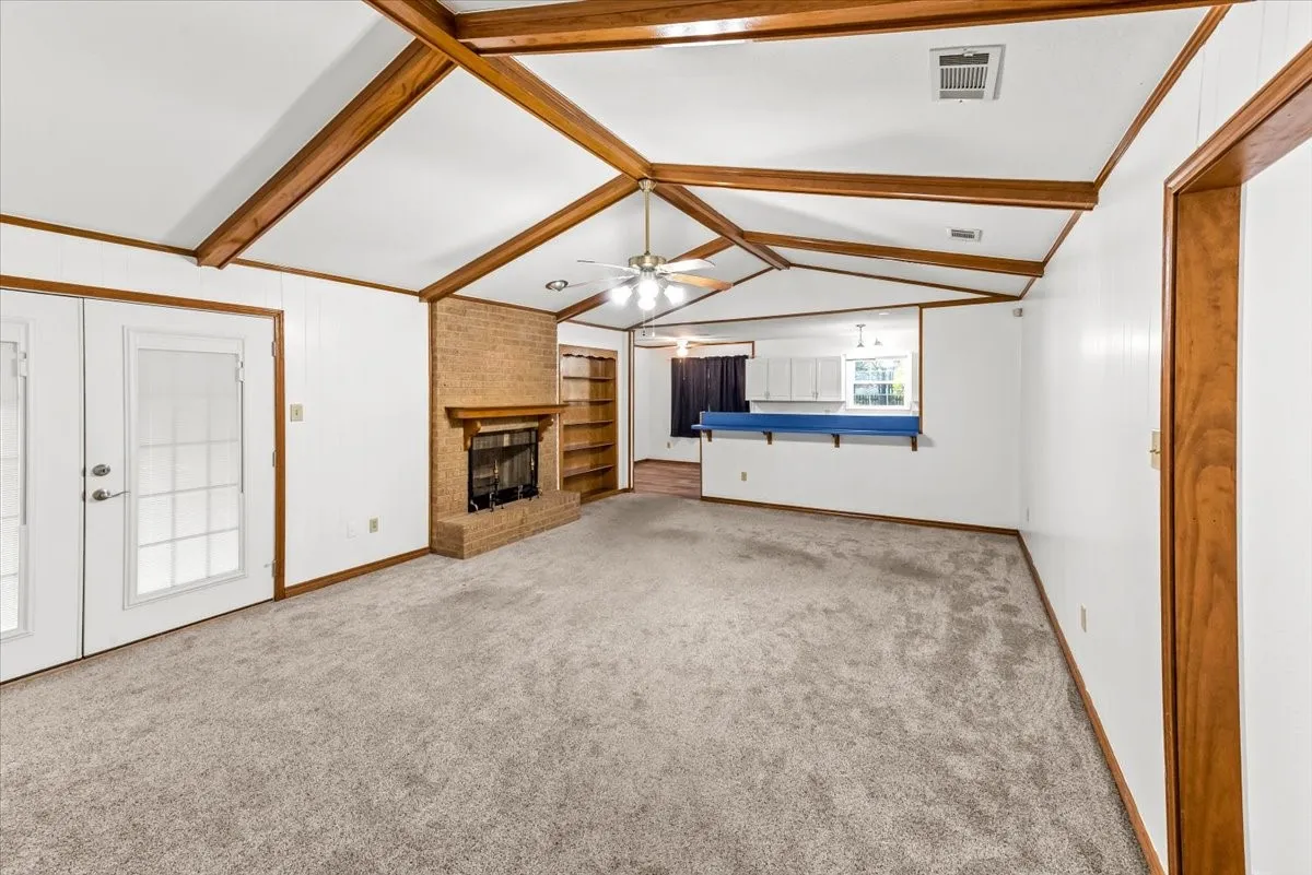 Unfurnished living room featuring a fireplace, carpet, french doors, and built in shelves