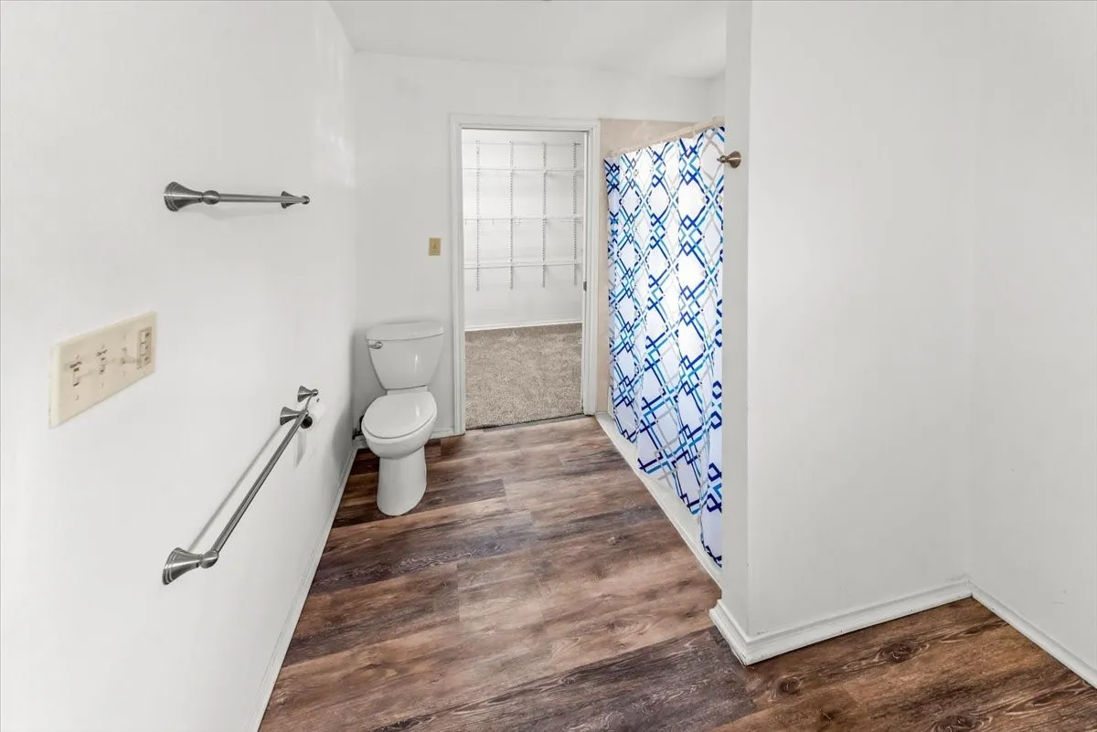 Primary bath featuring curtained shower and dark wood finished floors