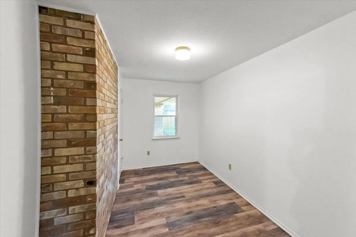 Spare room featuring brick wall and vinyl floors