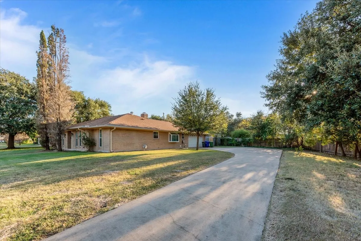 View of home's exterior with driveway, a chimney, brick siding, and an attached garage