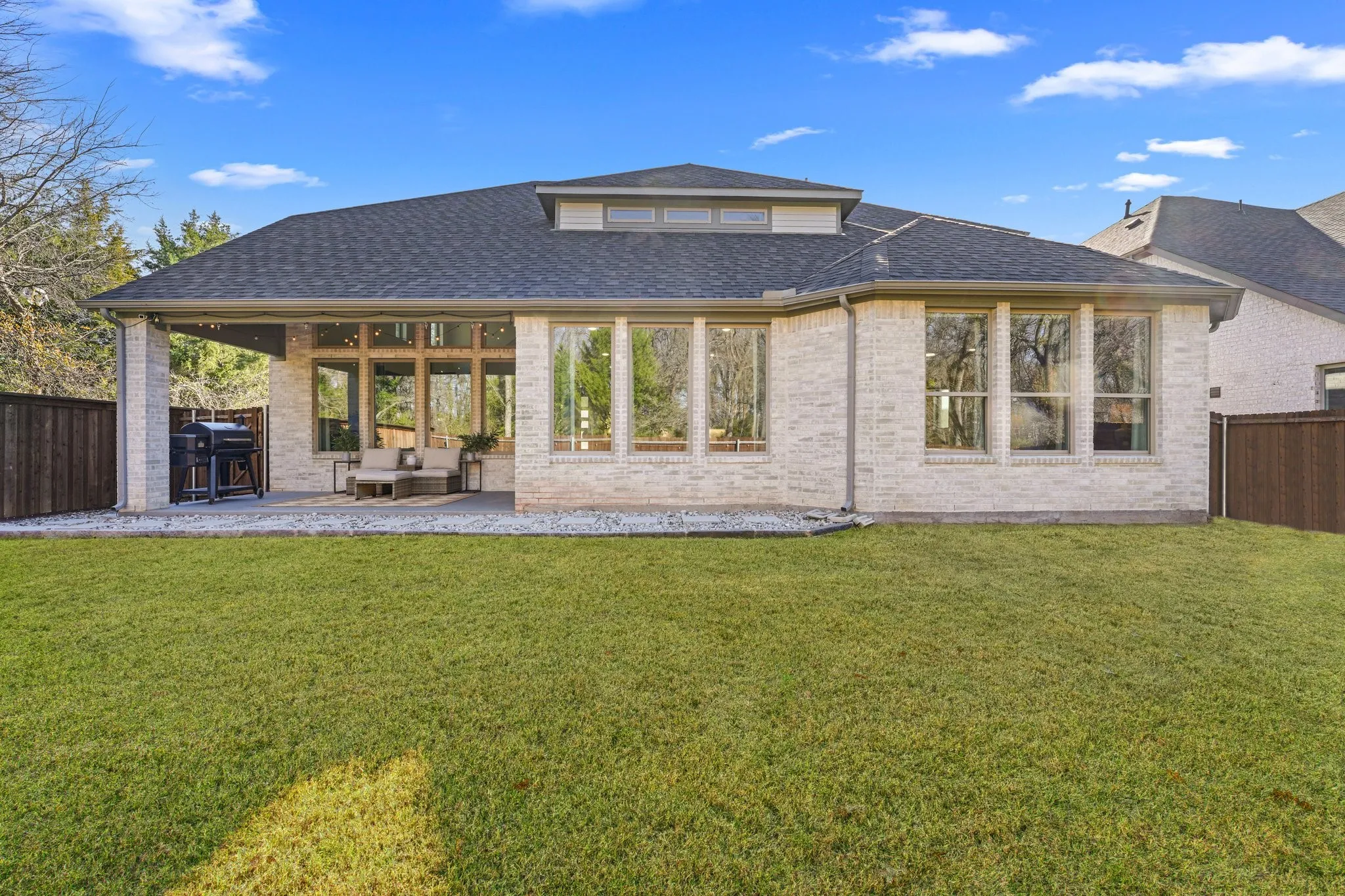 Back of property with a fenced backyard, a patio, a shingled roof, and brick siding