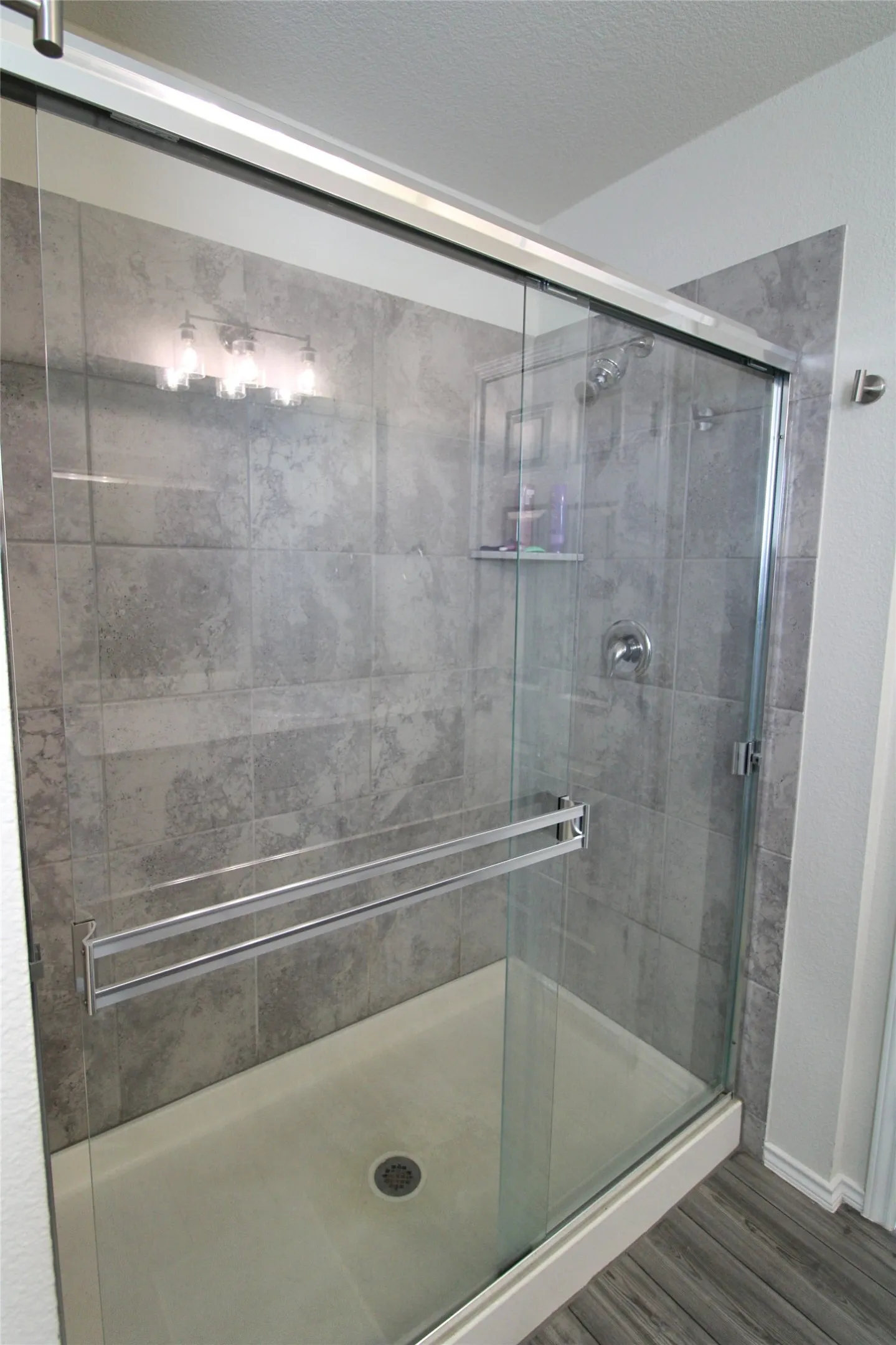 Bathroom featuring a shower stall, wood finished floors, and a textured ceiling