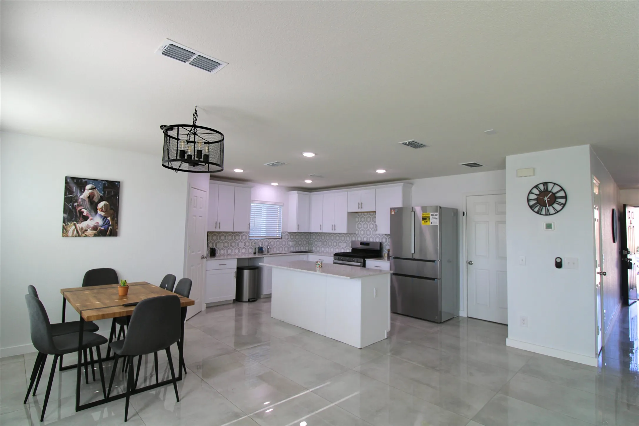 Kitchen with stainless steel appliances, white cabinetry, a center island, backsplash, and recessed lighting