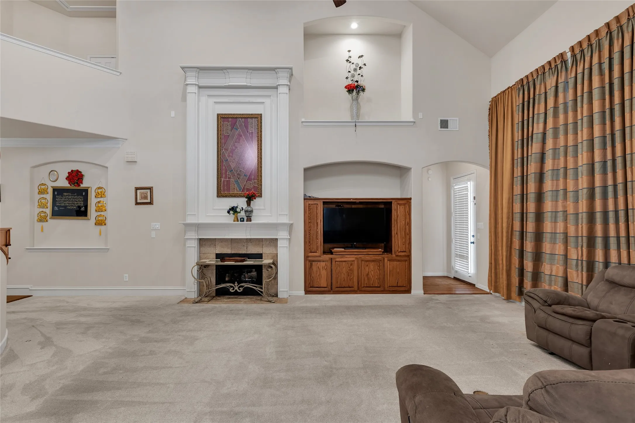 Carpeted living room featuring high vaulted ceiling, a tile fireplace, and arched walkways