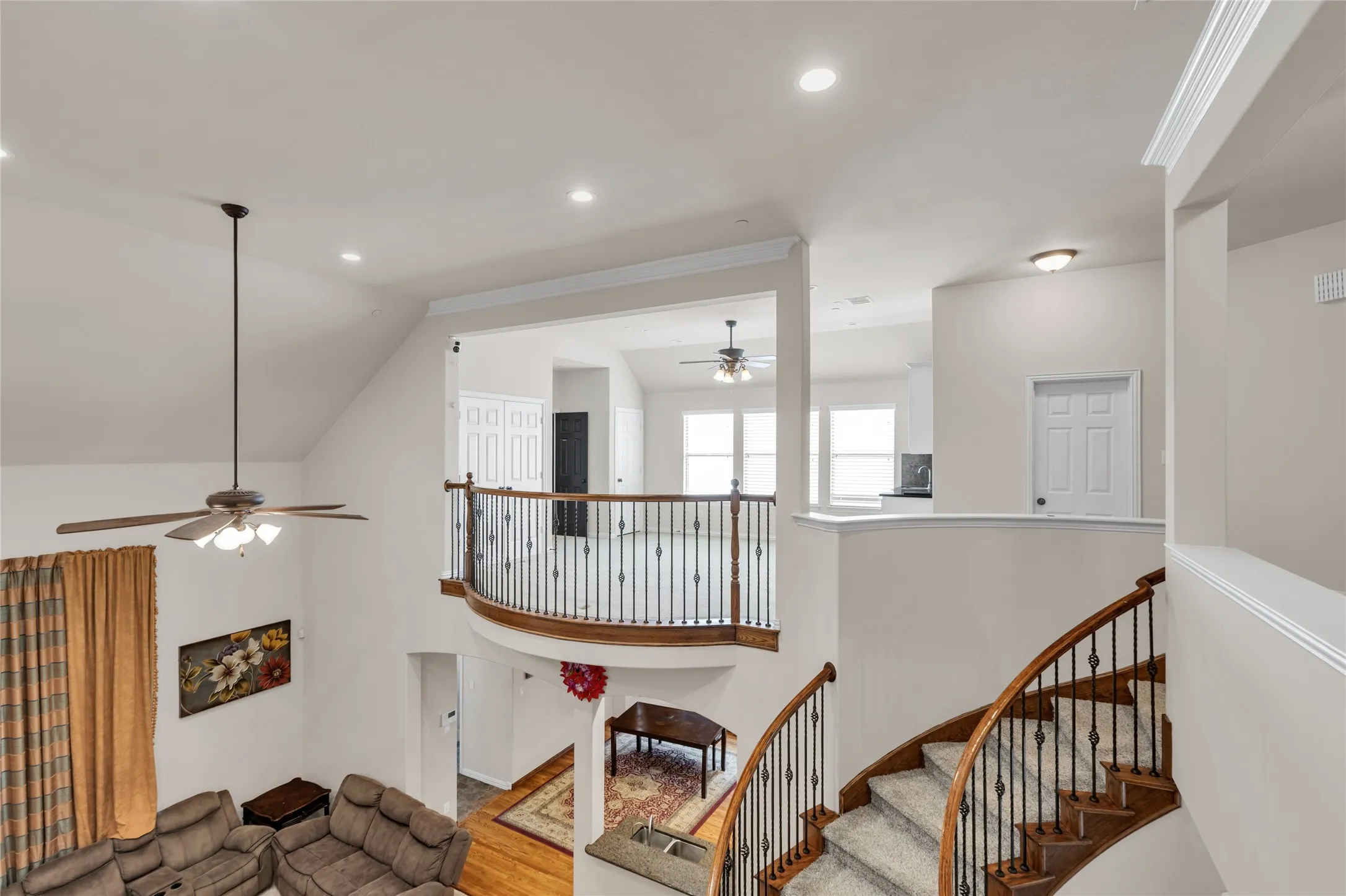 Stairs featuring a ceiling fan, a high ceiling, recessed lighting, and wood finished floors
