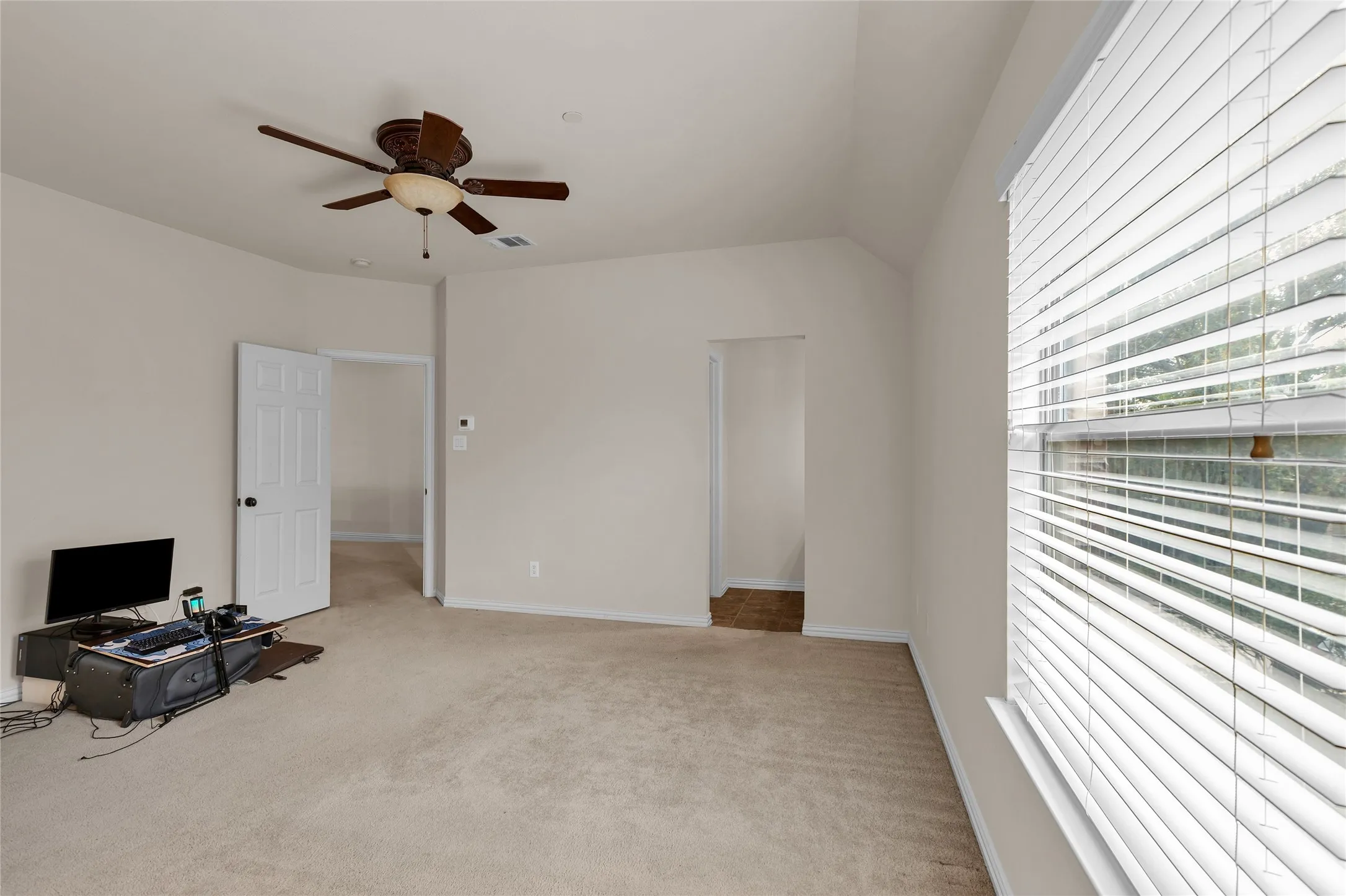 Unfurnished bedroom with light colored carpet, a ceiling fan, and lofted ceiling