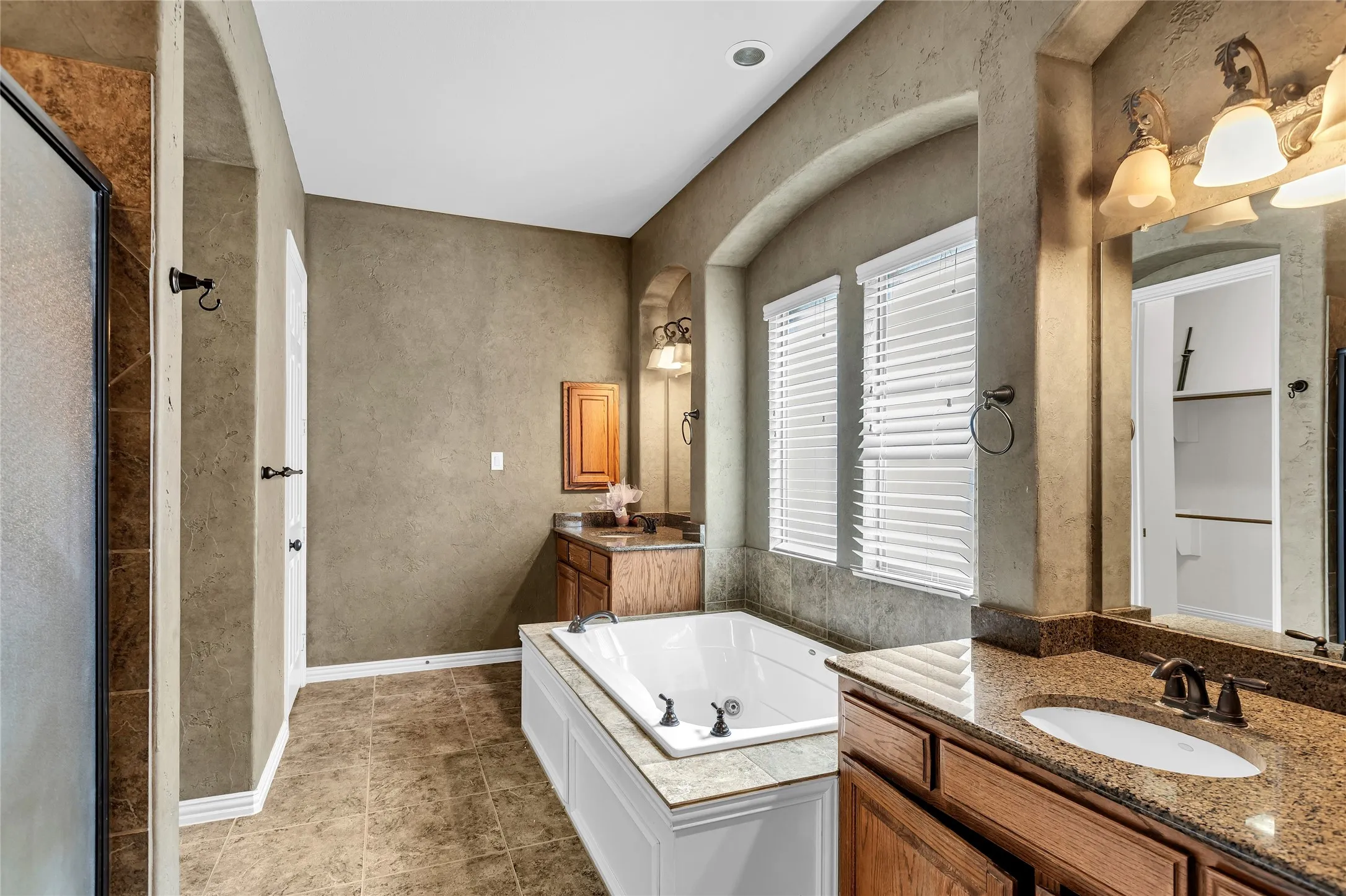 Bathroom featuring two vanities, a bath, and a shower stall