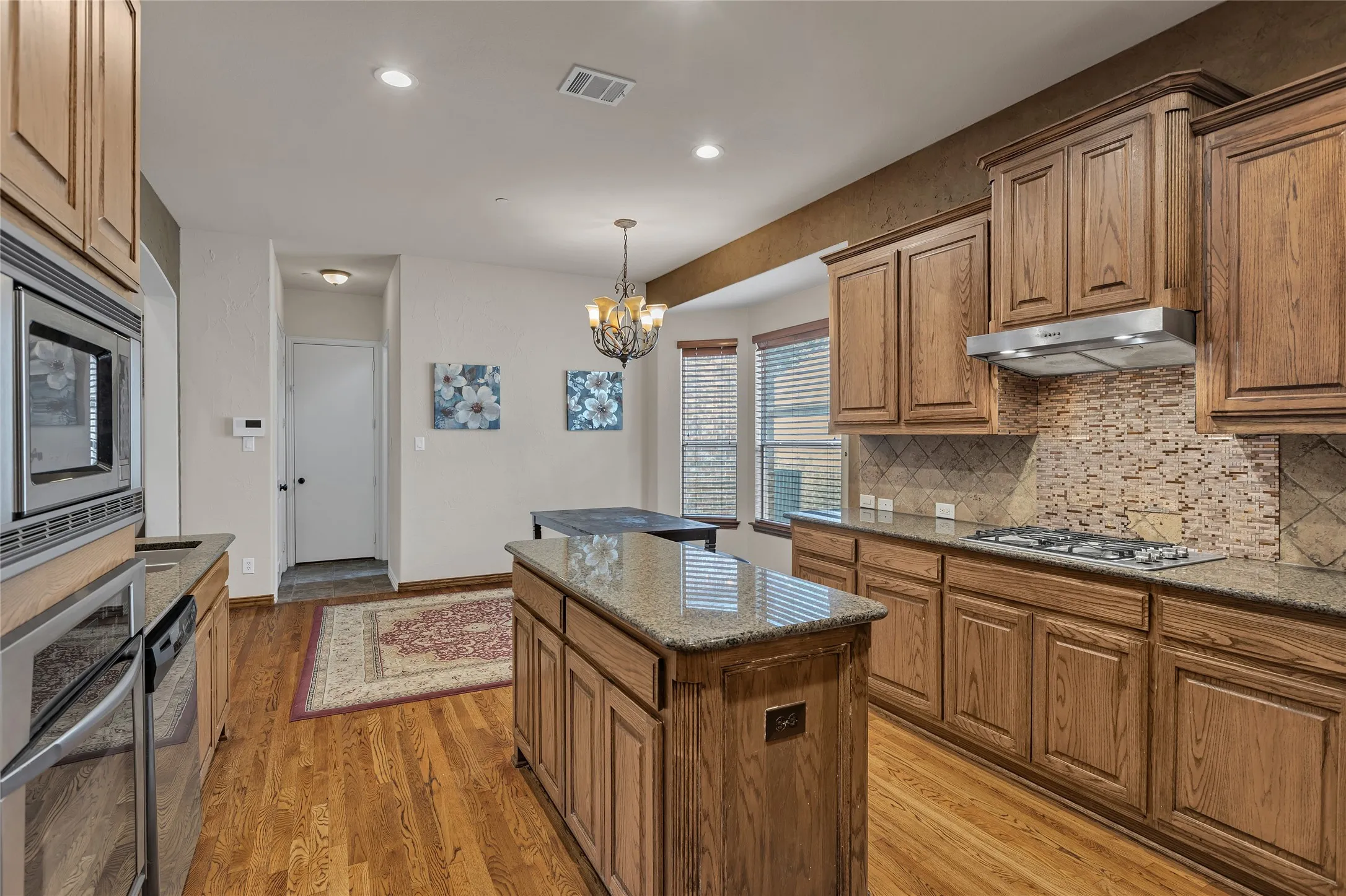 Kitchen featuring a center island, dark stone countertops, hanging light fixtures, appliances with stainless steel finishes, and brown cabinets