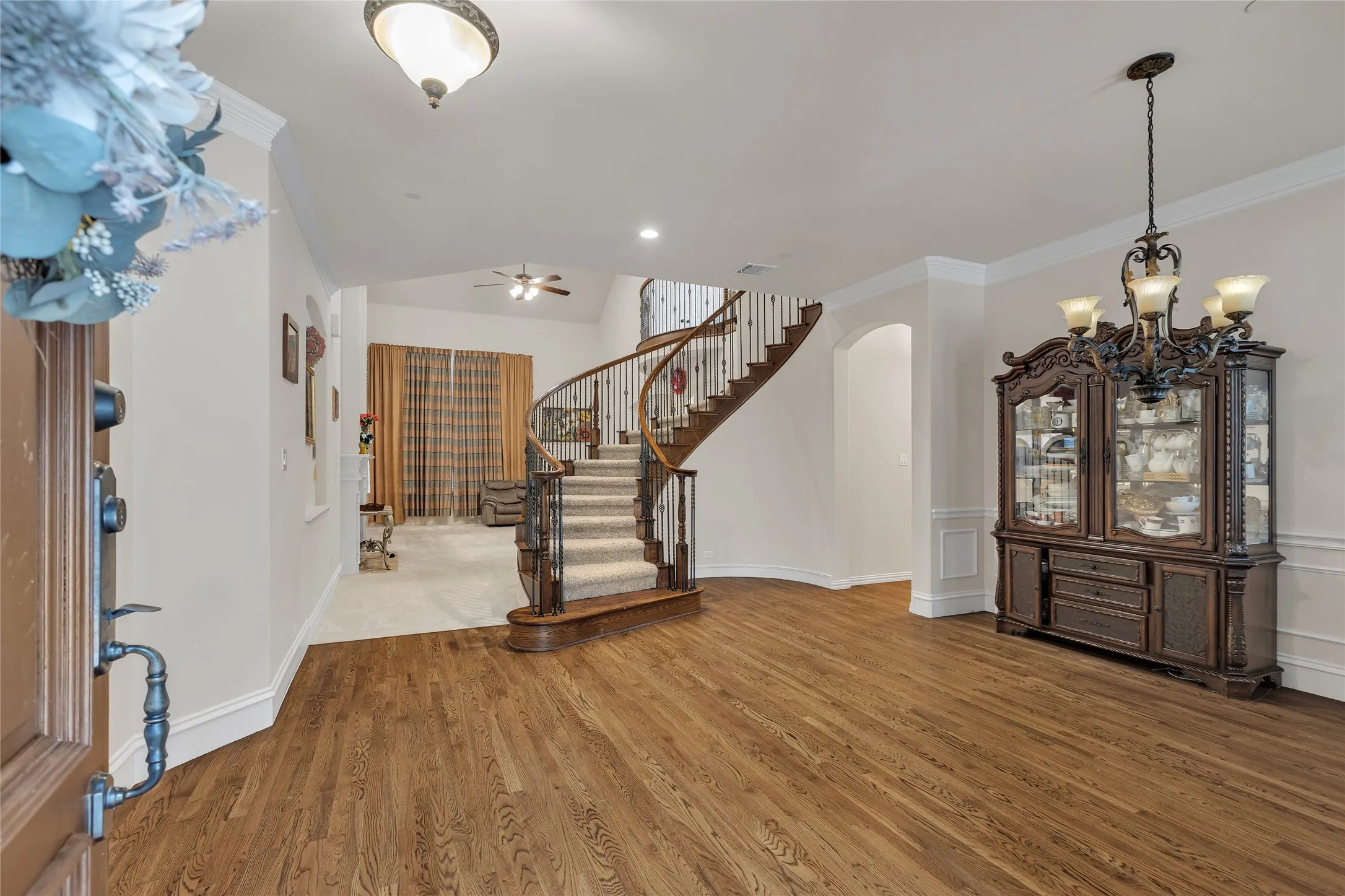 Foyer entrance with wood finished floors, arched walkways, stairs, ornamental molding, and a chandelier