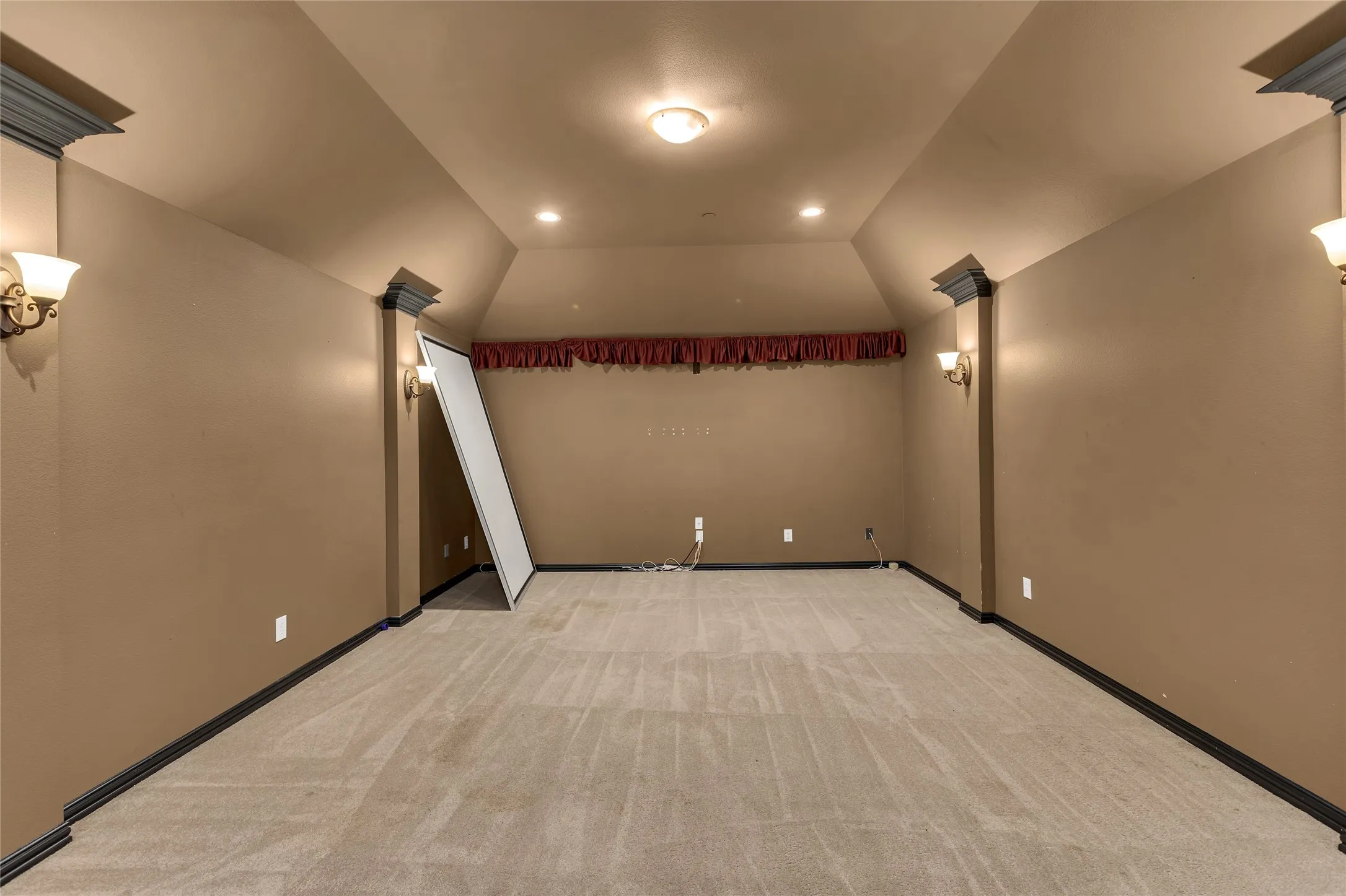 Cinema featuring light carpet and vaulted ceiling