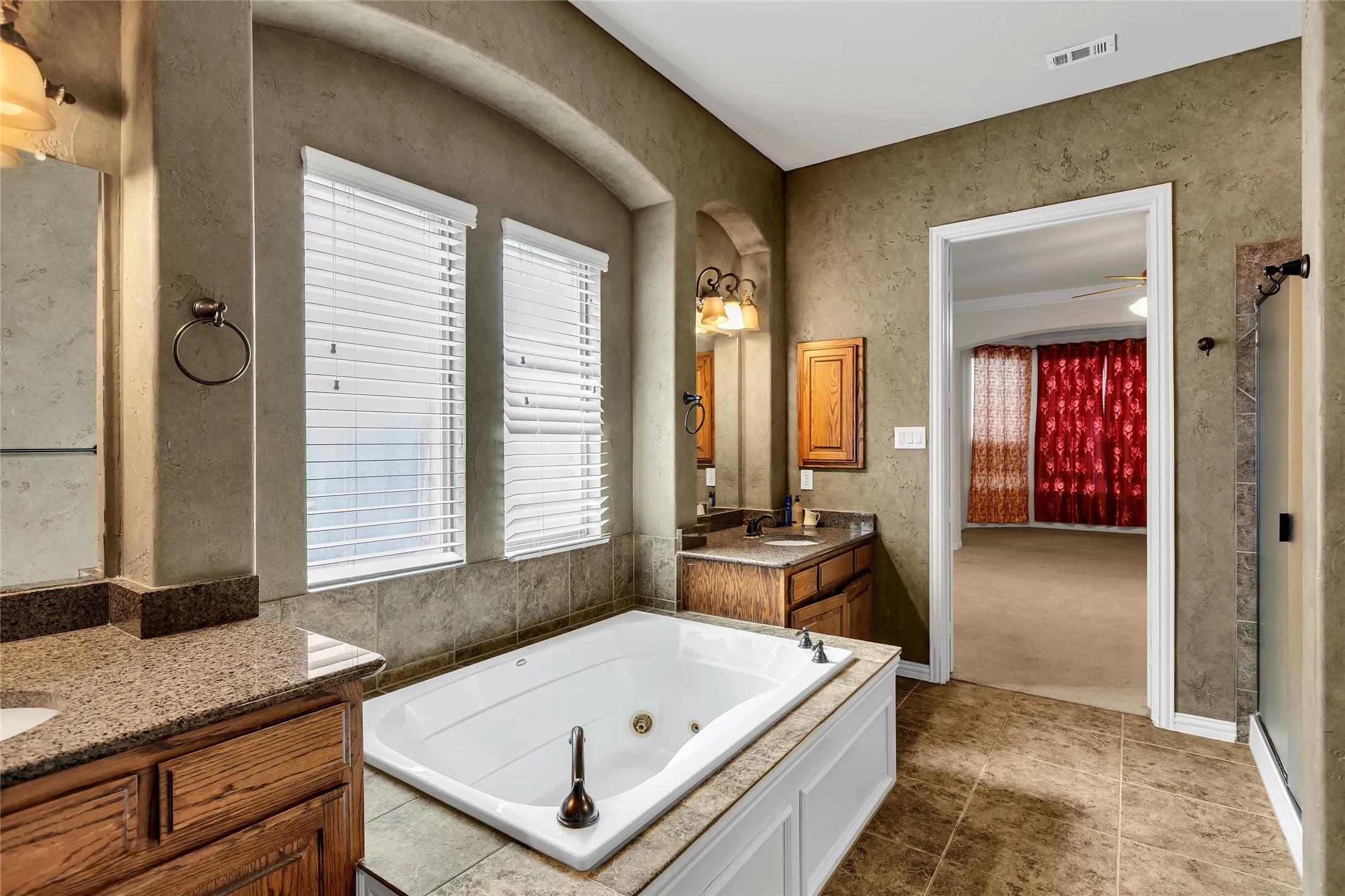 Full bath featuring two vanities, a jetted tub, a shower stall, and ornamental molding