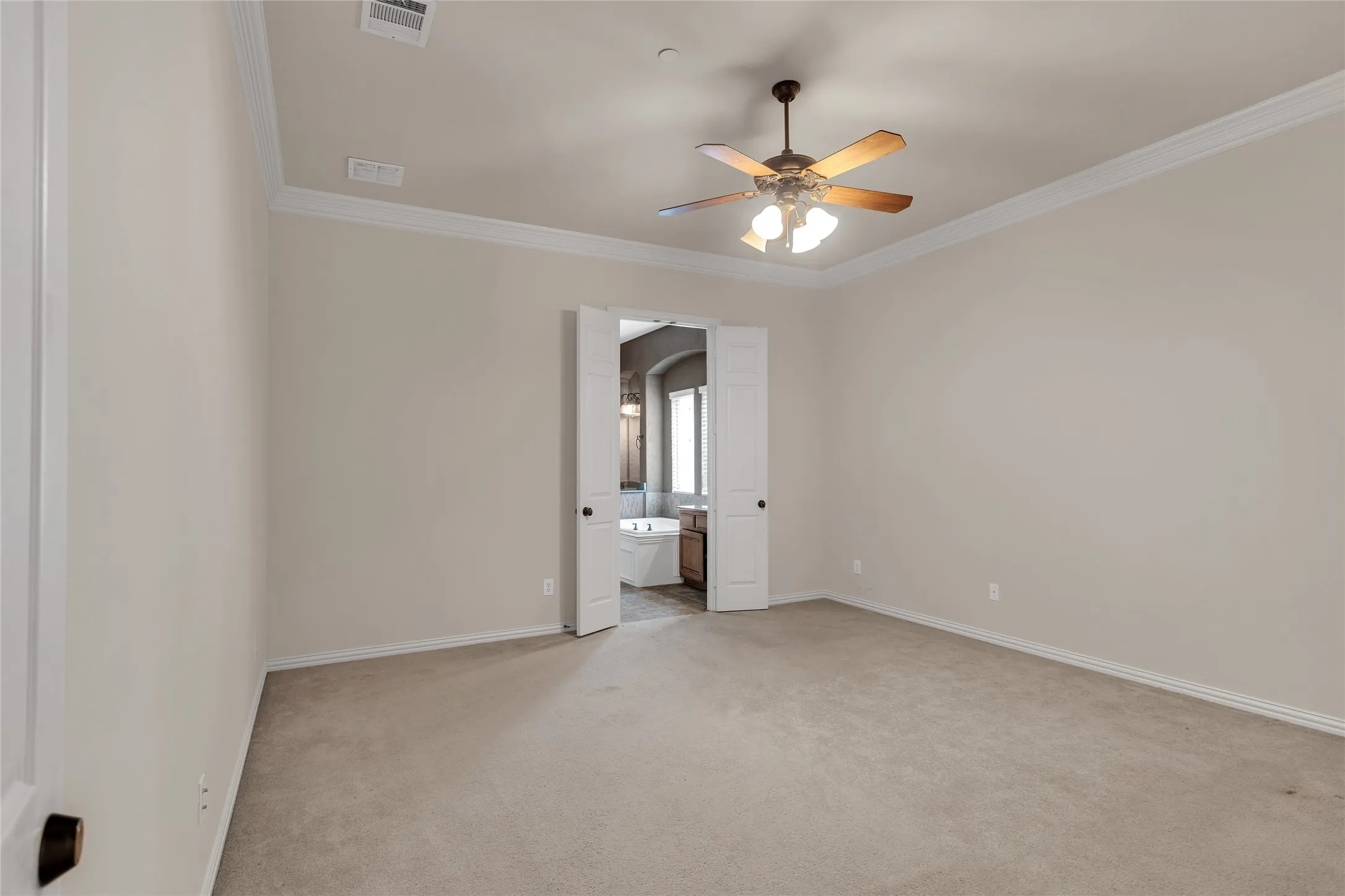 Spare room featuring light carpet, ceiling fan, crown molding, and arched walkways