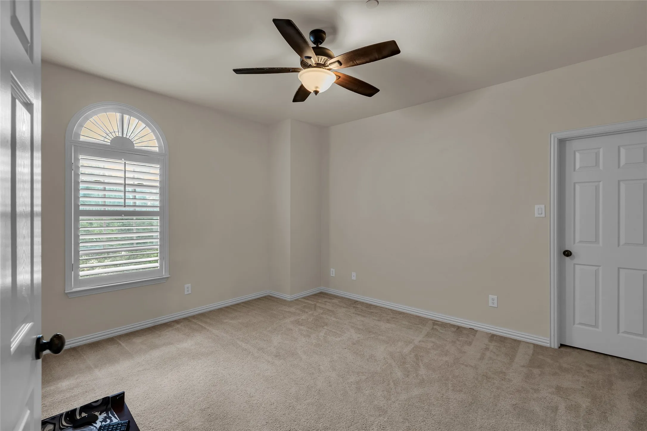 Empty room featuring light carpet and a ceiling fan