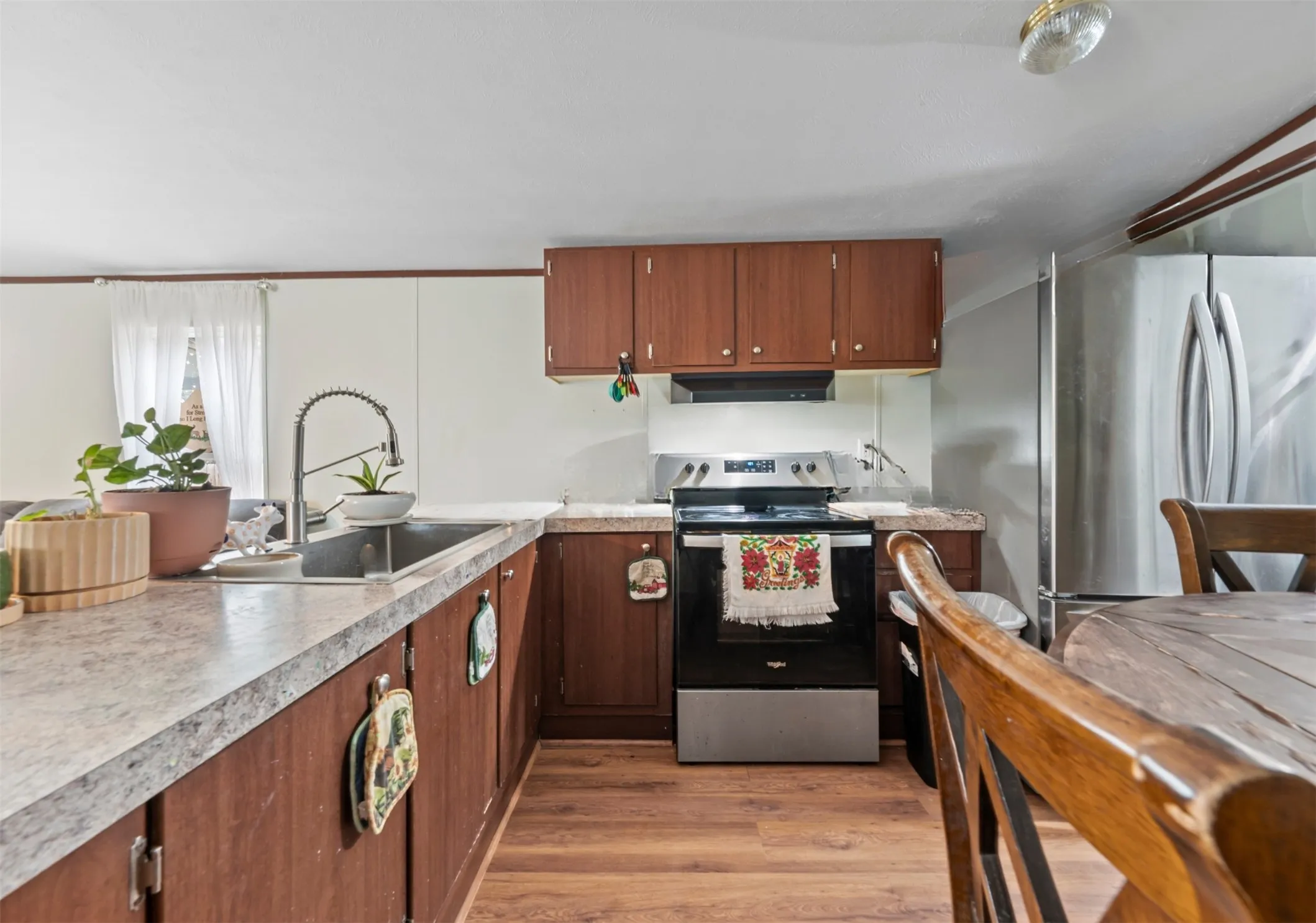 Kitchen featuring stainless steel appliances, light wood-style floors, light countertops, and brown cabinetry