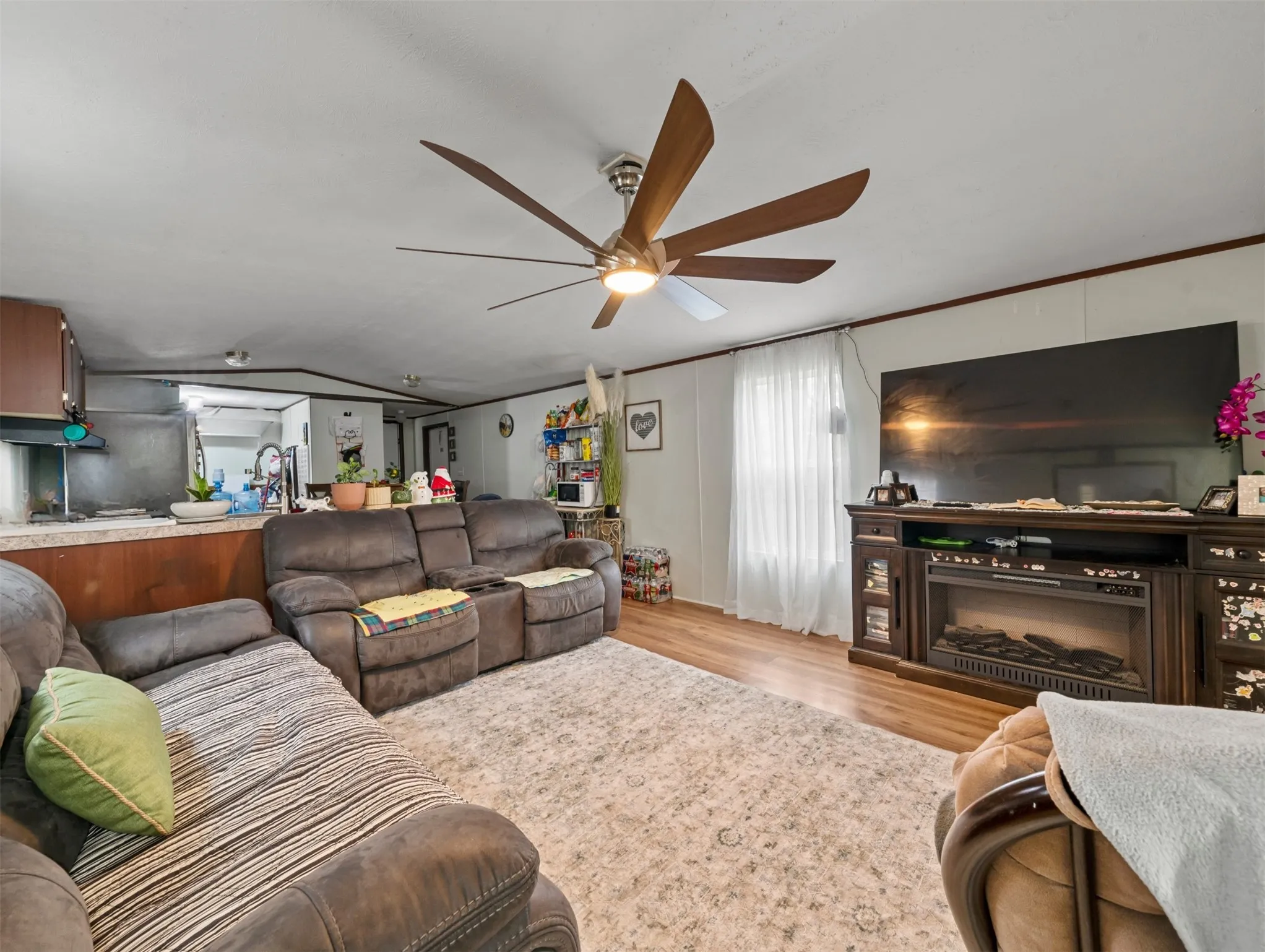 Living area featuring light wood-style flooring, ceiling fan, and ornamental molding
