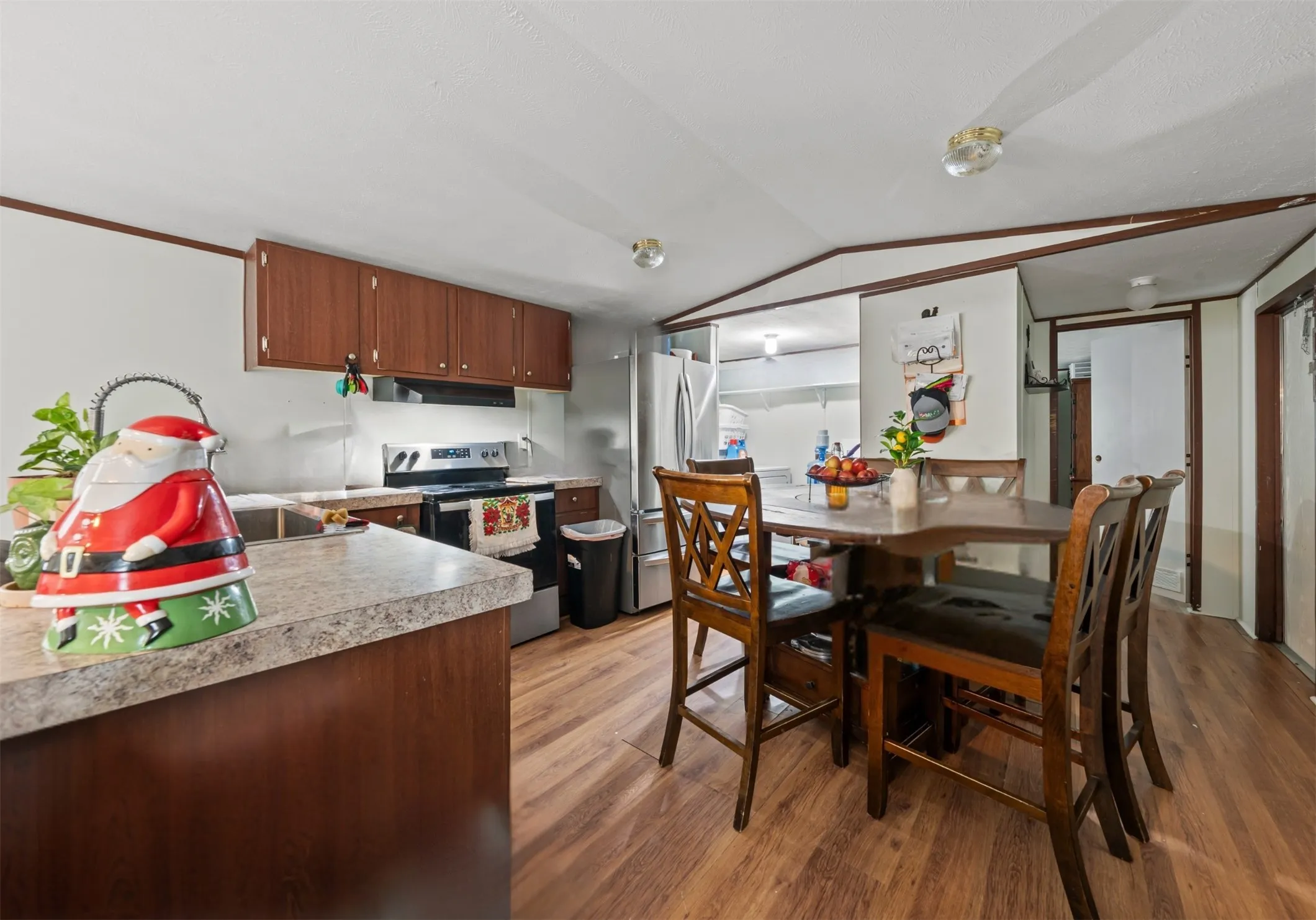 Kitchen featuring stainless steel appliances, light wood-style floors, light countertops, lofted ceiling, and under cabinet range hood