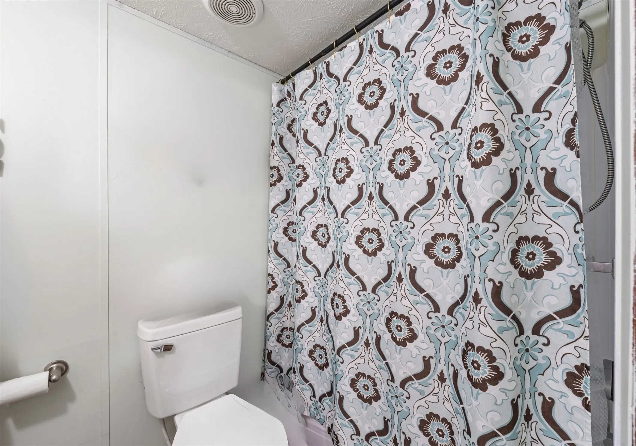 Full bathroom with a shower with curtain and a textured ceiling