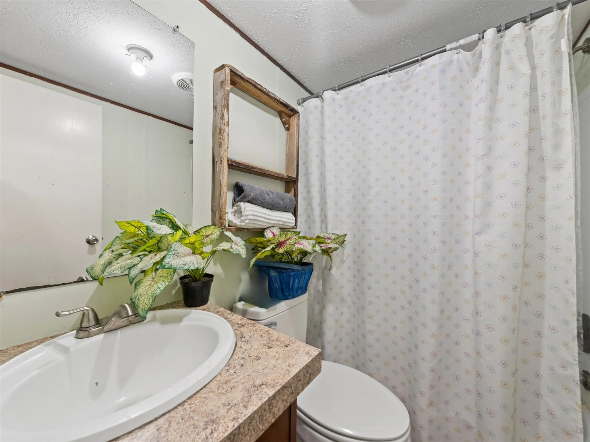 Full bathroom featuring a shower with shower curtain, vanity, a textured ceiling, and crown molding