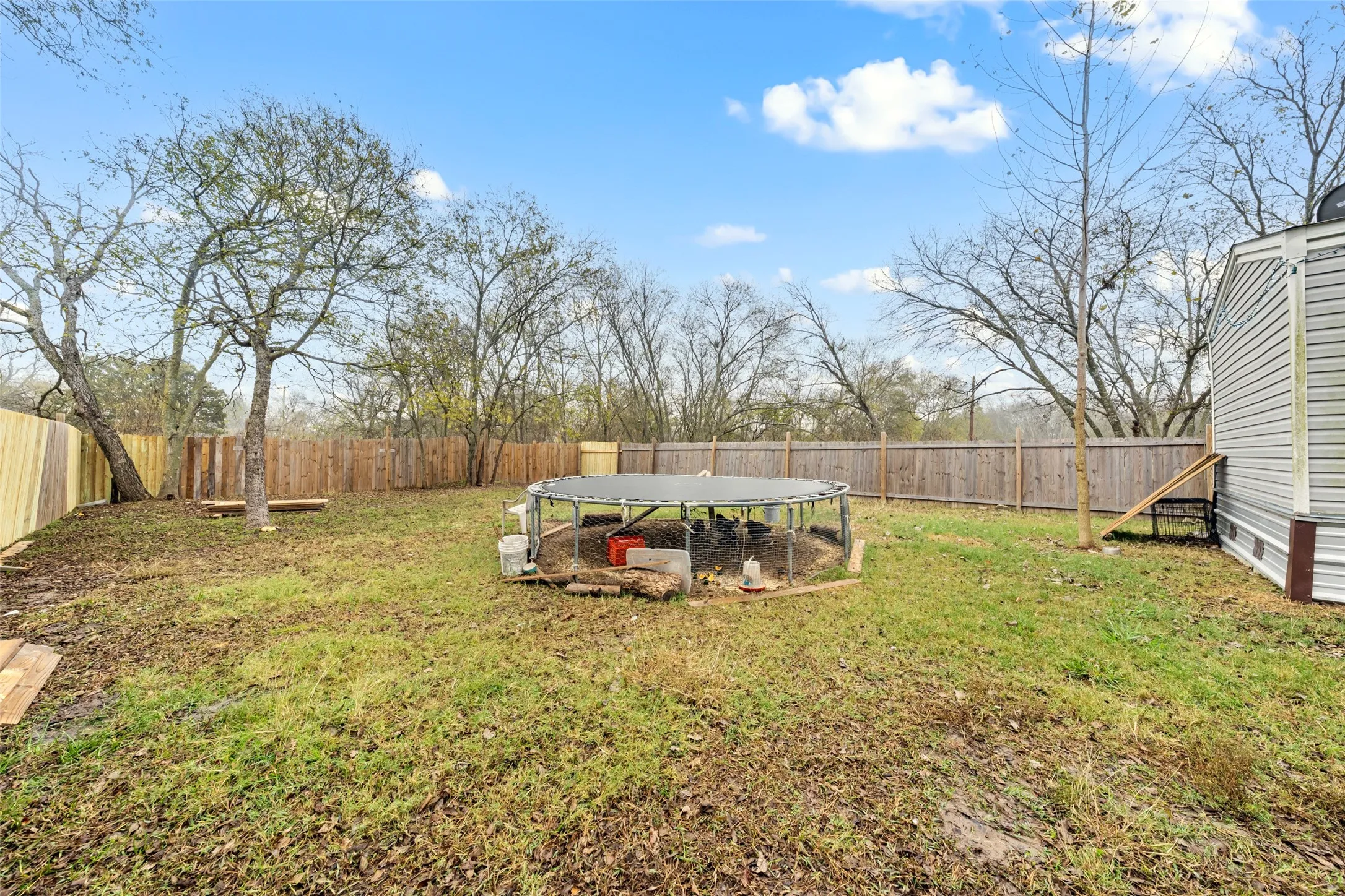 Fenced backyard featuring a trampoline and a patio area