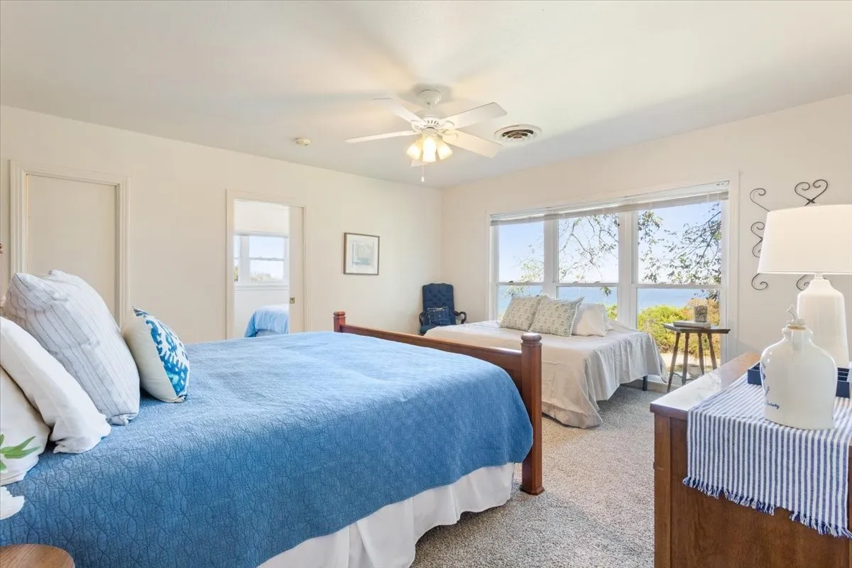 Bedroom featuring multiple windows, a water view, carpet, and a ceiling fan