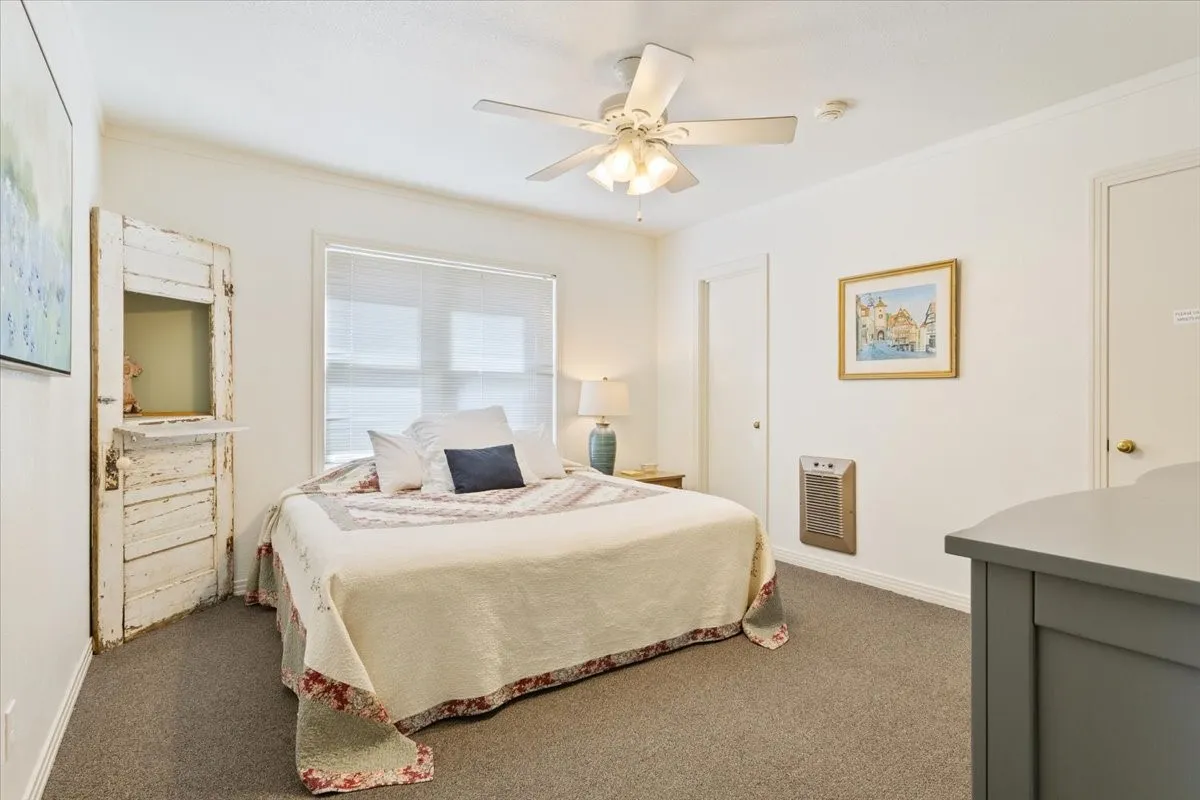 Carpeted bedroom featuring a ceiling fan and heating unit